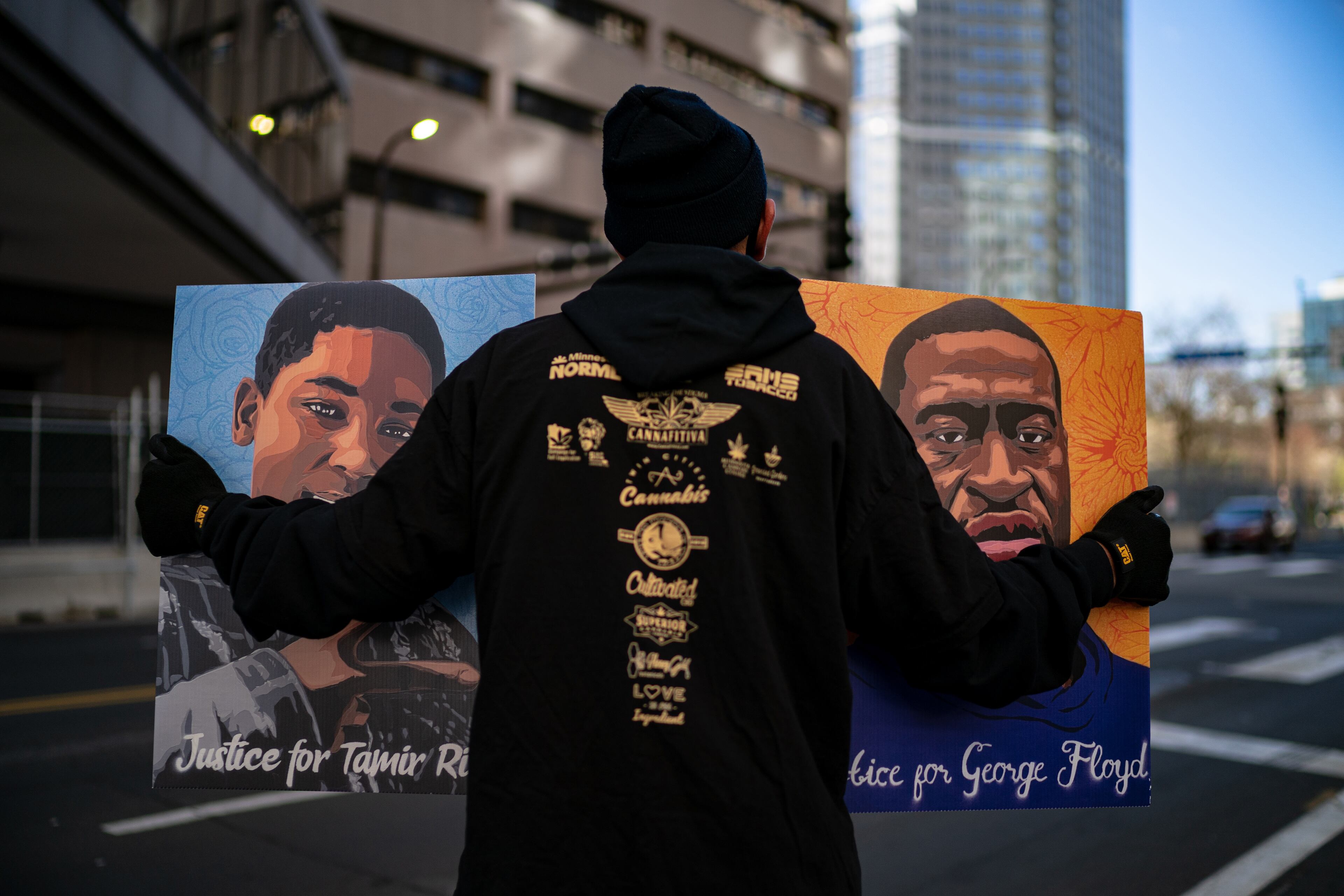 A man hold pictures of George Floyd and Tamir Rice outside the Hennepin Country Government Center in Minneapolis, Minn., on Tuesday, April 20, 2021, where the Derek Chauvin trial is taking place. Chauvin, a former police officer is charged in the death of George Floyd while in police custody last year. (Amr Alfiky/The New York Times)