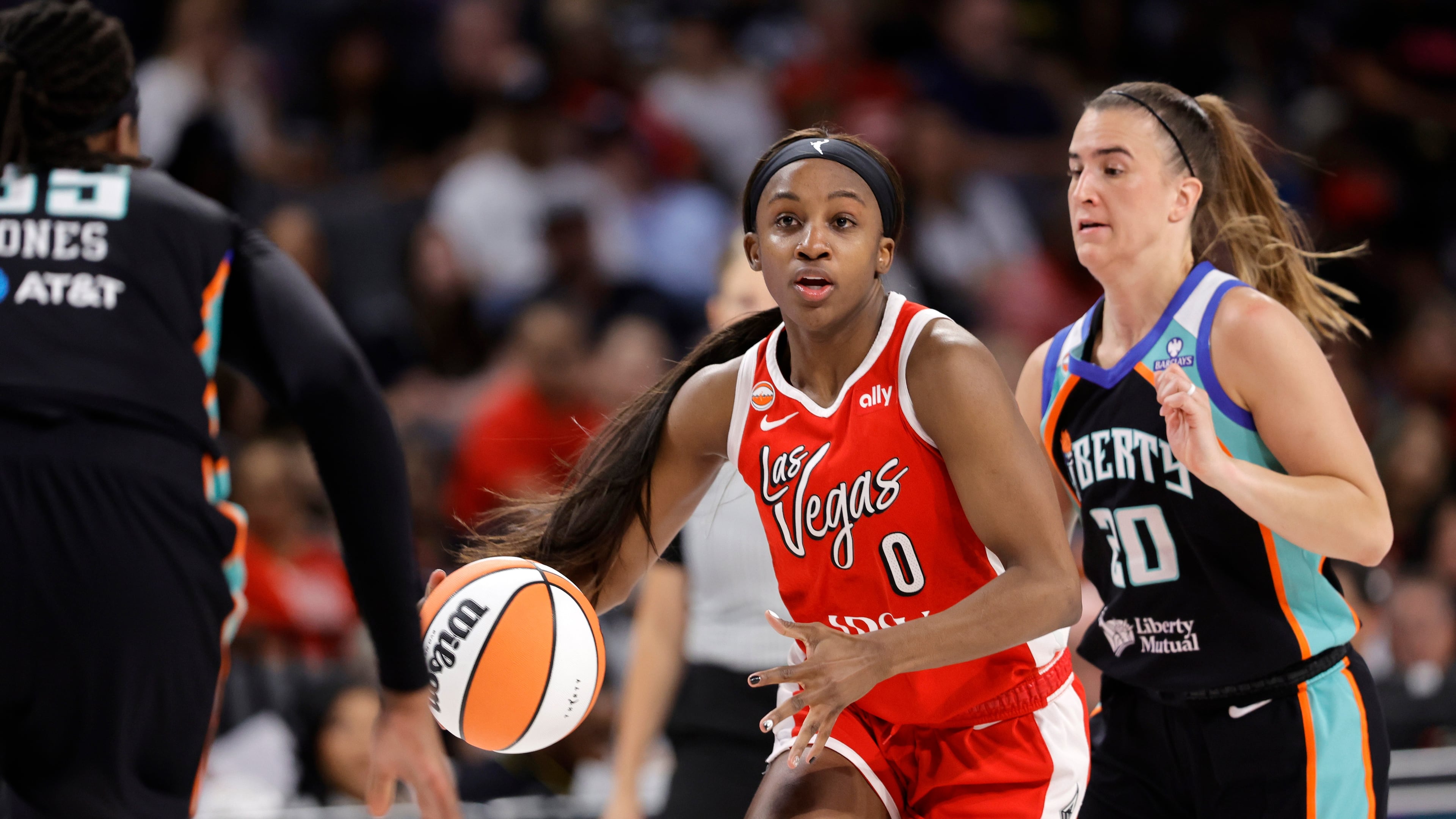 Las Vegas Aces guard Jackie Young (0) drives between New York Liberty center Jonquel Jones, left, and guard Sabrina Ionescu (20) during the first half of an WNBA basketball game Thursday, July 30, 2026, in Las Vegas. (Steve Marcus/Las Vegas Sun via AP)