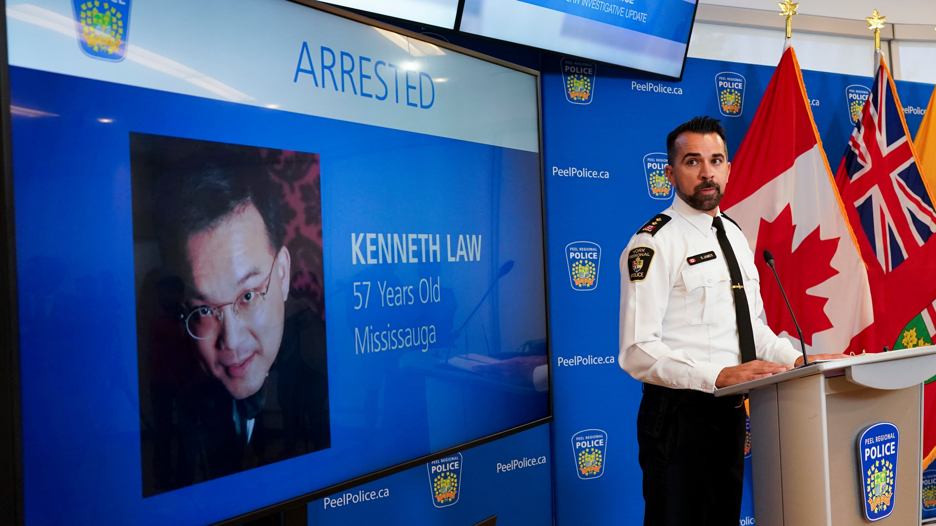 FILE - York Regional Police Inspector Simon James speaks during a news conference in Mississauga, Ontario, Aug. 29, 2023, with the image of Kenneth Law, a Canadian man accused of selling lethal substances on the internet to people at risk of self harm, displayed on screen. (Arlyn McAdorey/The Canadian Press via AP, File)