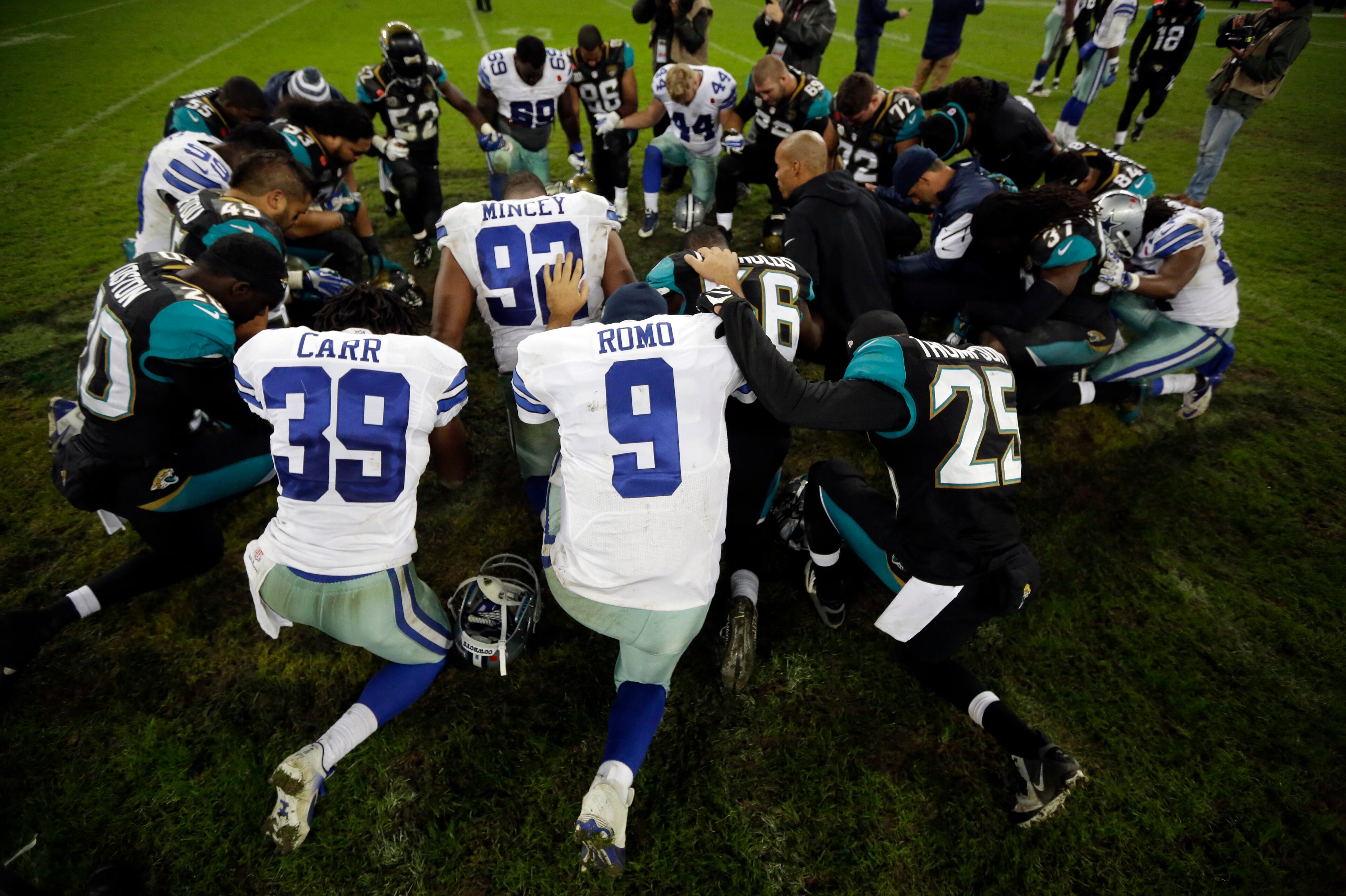 Dallas Cowboys quarterback Tony Romo (9) joins the Jacksonville Jaguars and teammates in a gathering following their NFL football game at Wembley Stadium, London, Sunday, Nov. 9, 2014. The Cowboys defeated the Jaguars 31-17. (AP Photo/Matt Dunham)