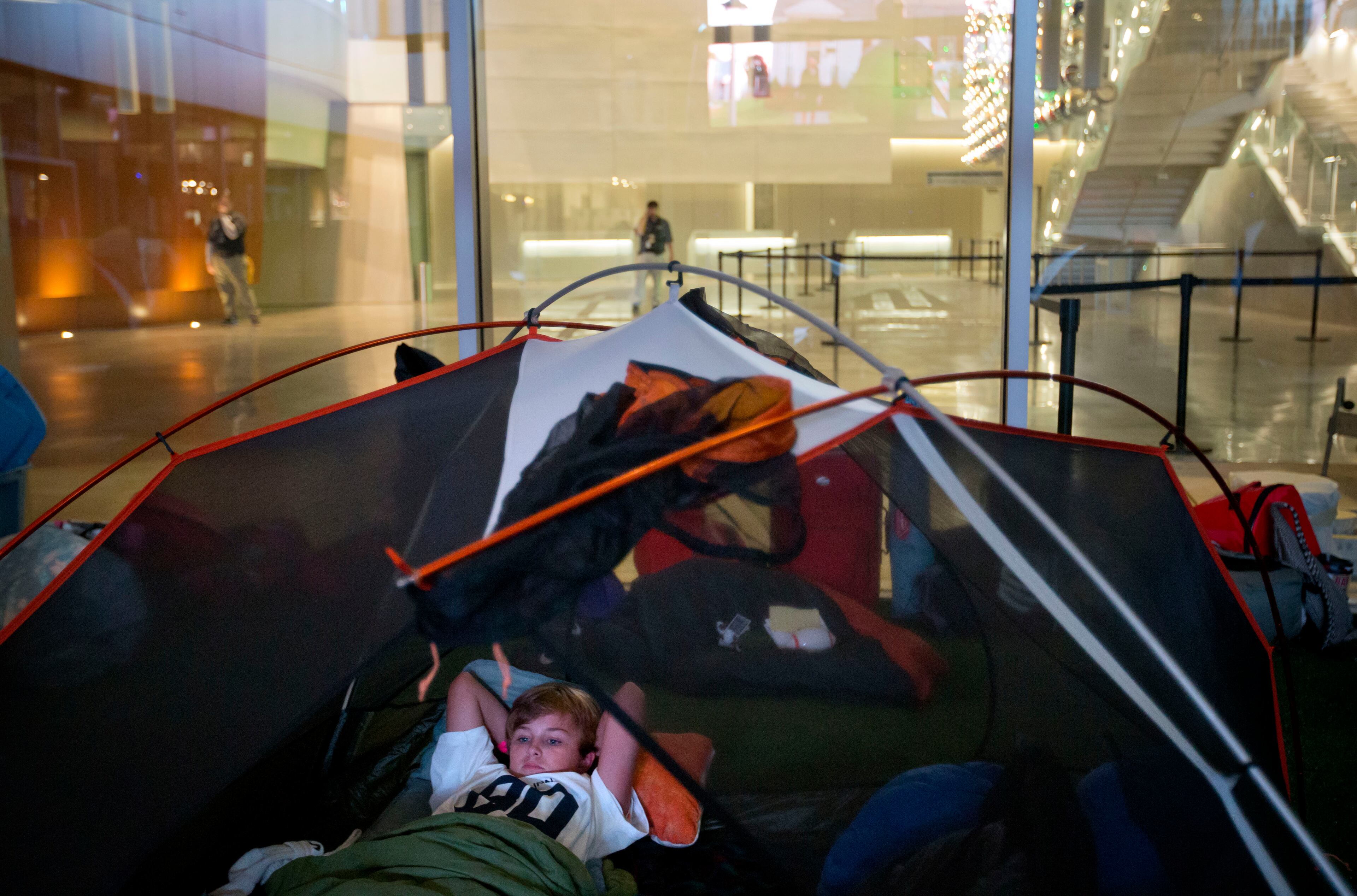 Parker Bertholf, 13, of Dunwoody, Ga., lies in his tent while watching the movie "Rudy" during a sleepover in the College Football Hall of Fame, Wednesday, Aug. 13, 2014, in Atlanta. Parker left the sleepover around sunrise with his dad who then took him to school for the opening bell around 8 a.m. (AP Photo/David Goldman)