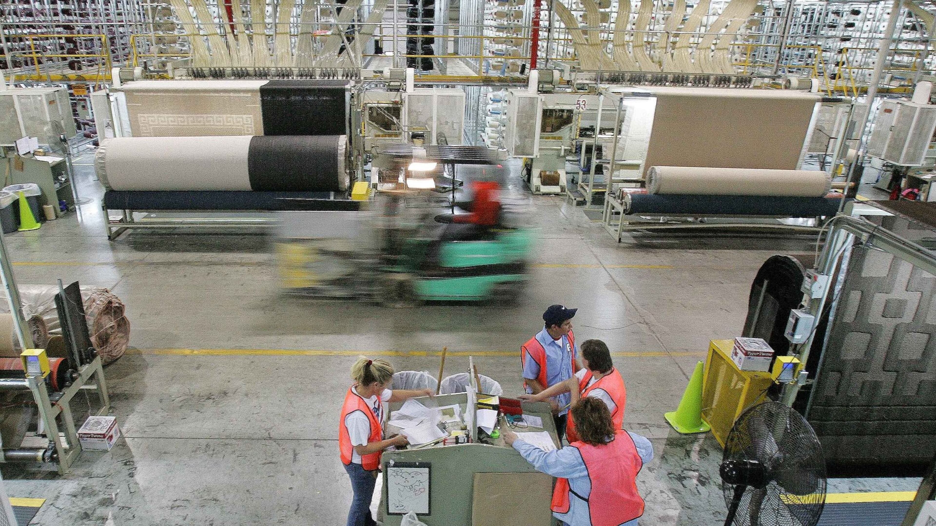 A forklift speeds by machines and workers on the production floor of a Mohawk Industries rug manufacturing plant in Calhoun, Ga., in 2006. Recently, the company has faced allegations that it inflated financial results, misleading investors. (AP Photo/Ric Feld)