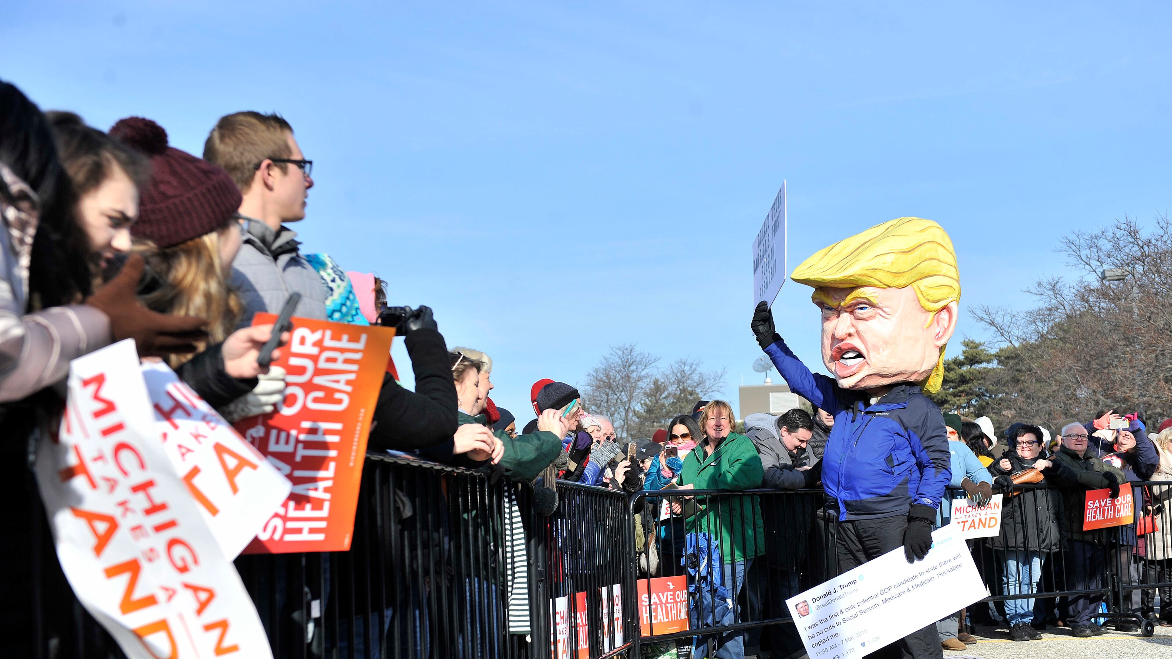 In a Sunday, Jan. 15, 2017 photo, A person dressed as Donald Trump waves before a rally for health care at Macomb Community College in Warren, Mich. Thousands of people showed up in freezing temperatures on Sunday in Michigan to hear Sanders denounce Republican efforts to repeal President Barack Obama's health care law, one of dozens of rallies Democrats staged across the country to highlight opposition. (Robin Buckson/The Detroit News via AP)