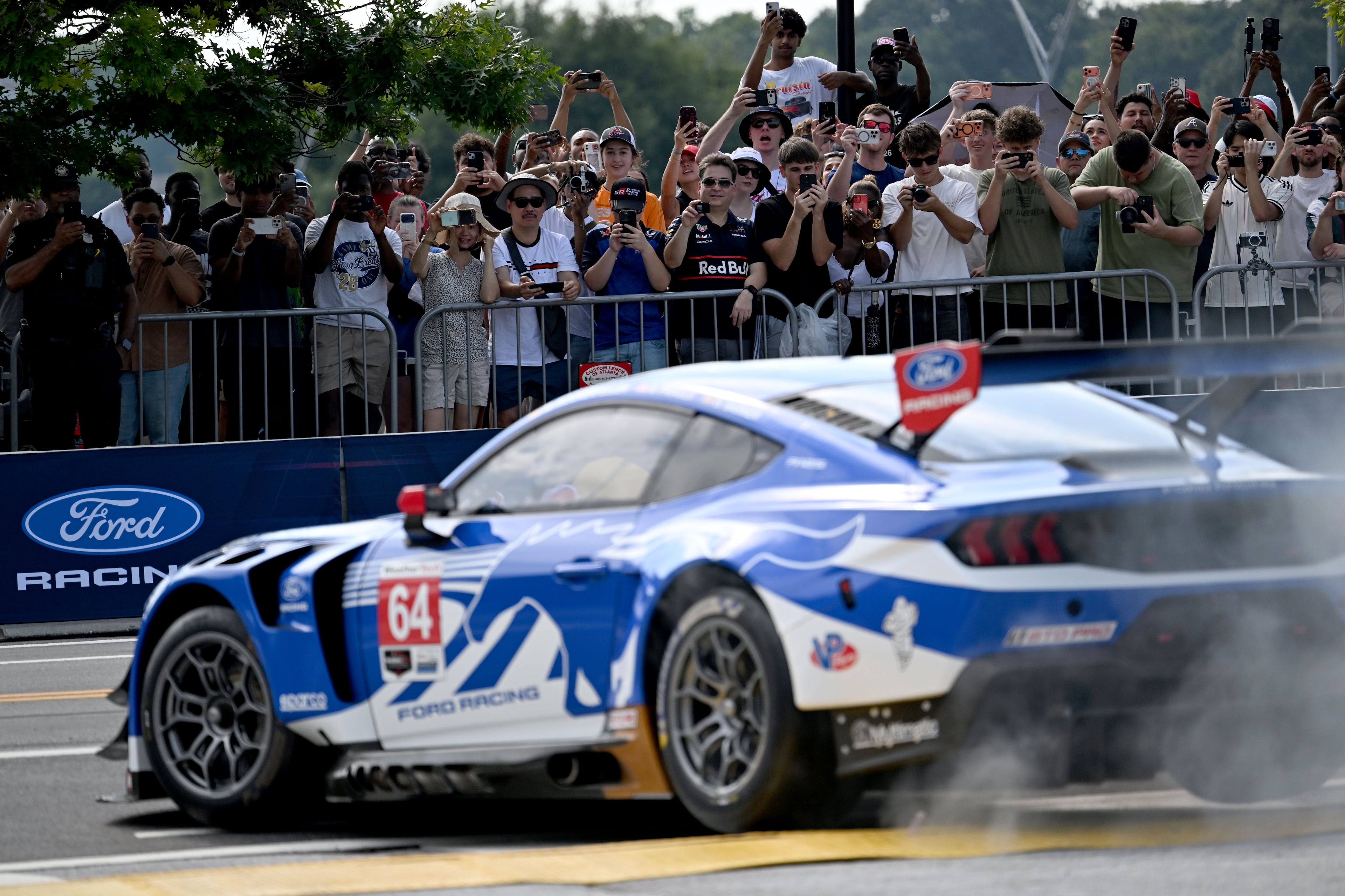 Spectators hold up their smartphones to capture a demonstration run on Hank Aaron Drive during the Red Bull Showrun Atlanta Presented by Ford Racing on Saturday, Aug. 1, 2026, in Atlanta. Atlanta city officials this week approved permits for the Red Bull Showrun that will allow the live motorsports demonstration event to go on as advertised along a roughly half-mile stretch of Hank Aaron Drive — a backup location after earlier plans to hold the event near Piedmont Park ran into opposition from Midtown residents. (Hyosub Shin/AJC)