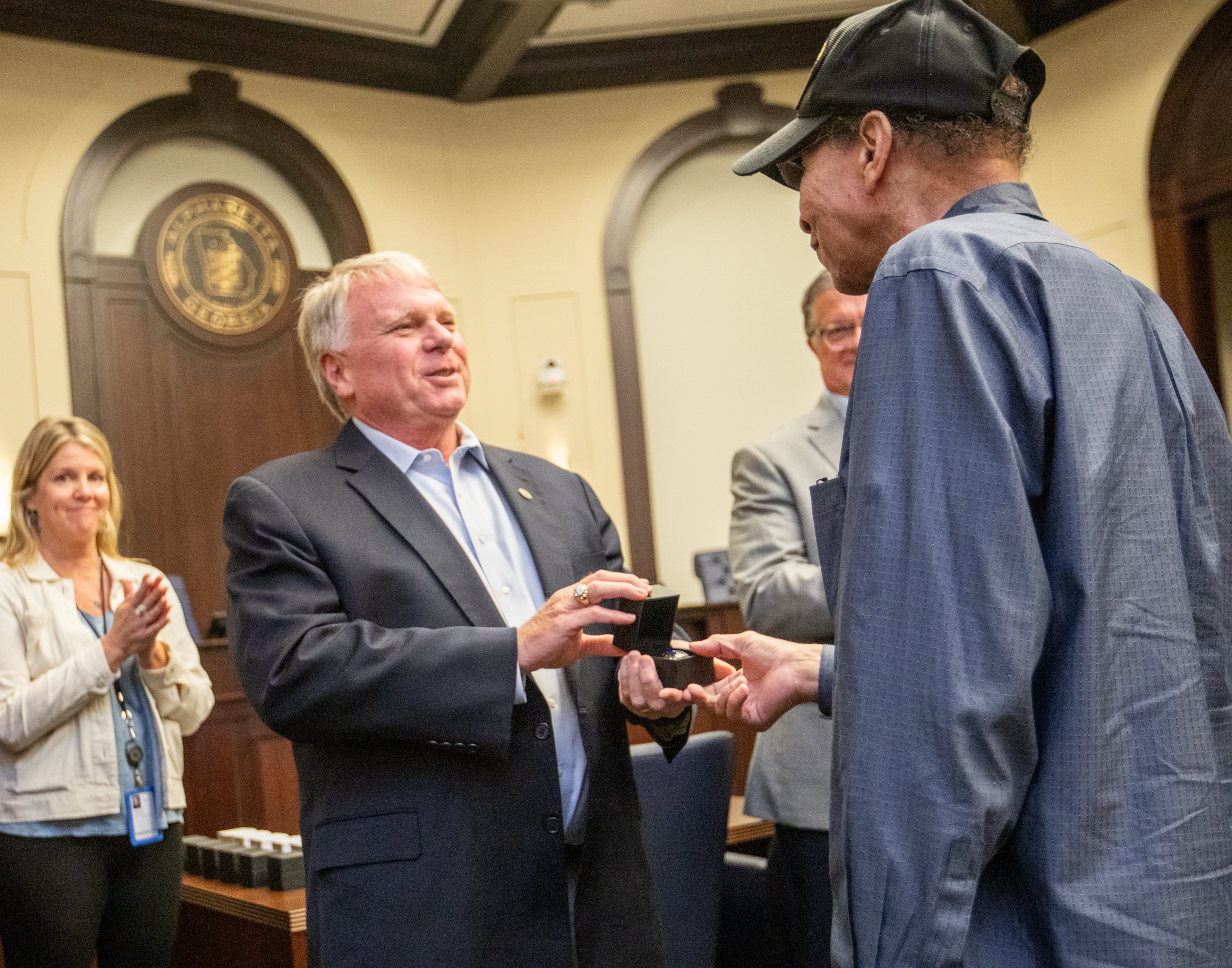 Alpharetta Mayor Jim Galvin, left, presents a State Championship ring to James Emerson, one of the Bailey-Johnson High School's basketball team of 1964-65 on Monday during the Alpharetta City Council meeting. (Jenni Girtman for The Atlanta Journal-Constitution)