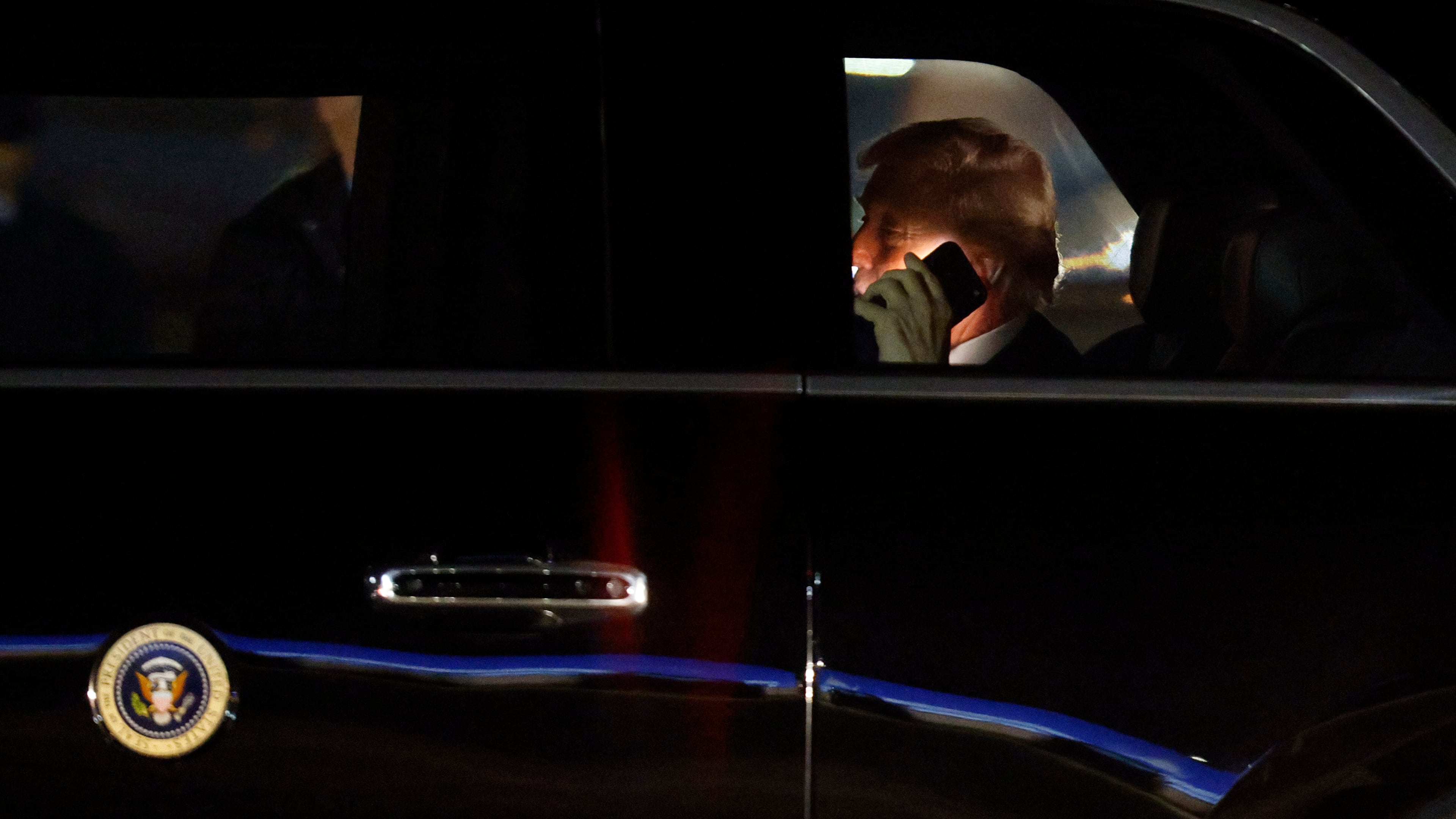 FILE - President Donald Trump talks on his cell phone in his limousine, known as "The Beast," upon his arrival at Joint Base Andrews, Md., March 6, 2026. (AP Photo/Luis M. Alvarez, File)