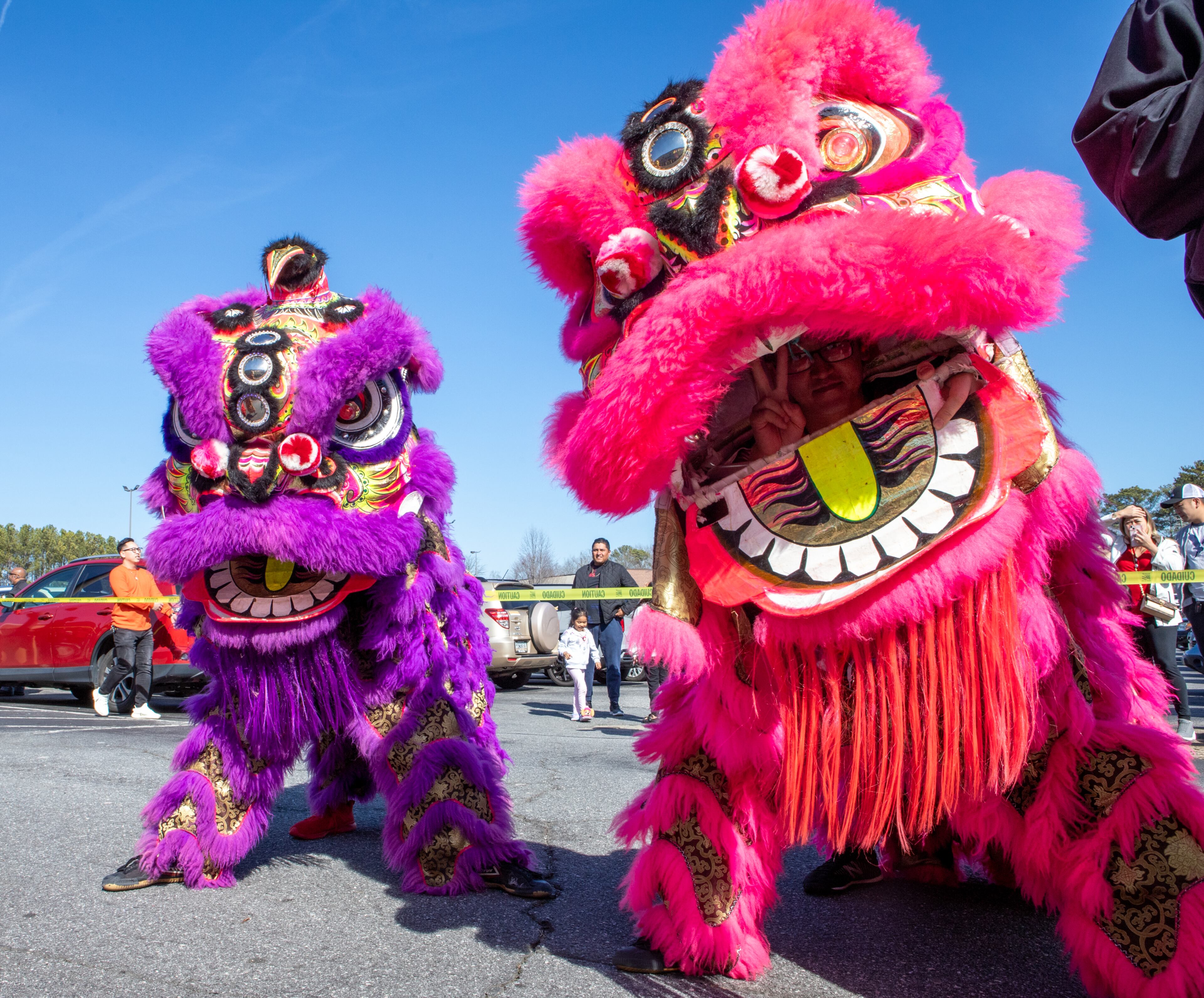 Lion dancers, including Alan Thao, right, wait and watch the ribbon cutting before they continue their dance and parade inside to the stage on Saturday, Feb 3, 2024. The Vietnamese American Community of Georgia hosts a Lunar New Year celebration at Plaza Las Americas in Lilburn on where dragon and lion dancing begins the weekend. The celebration continues on Sunday and includes traditional food, music and cultural festivities. (Jenni Girtman for The Atlanta Journal-Constitution)