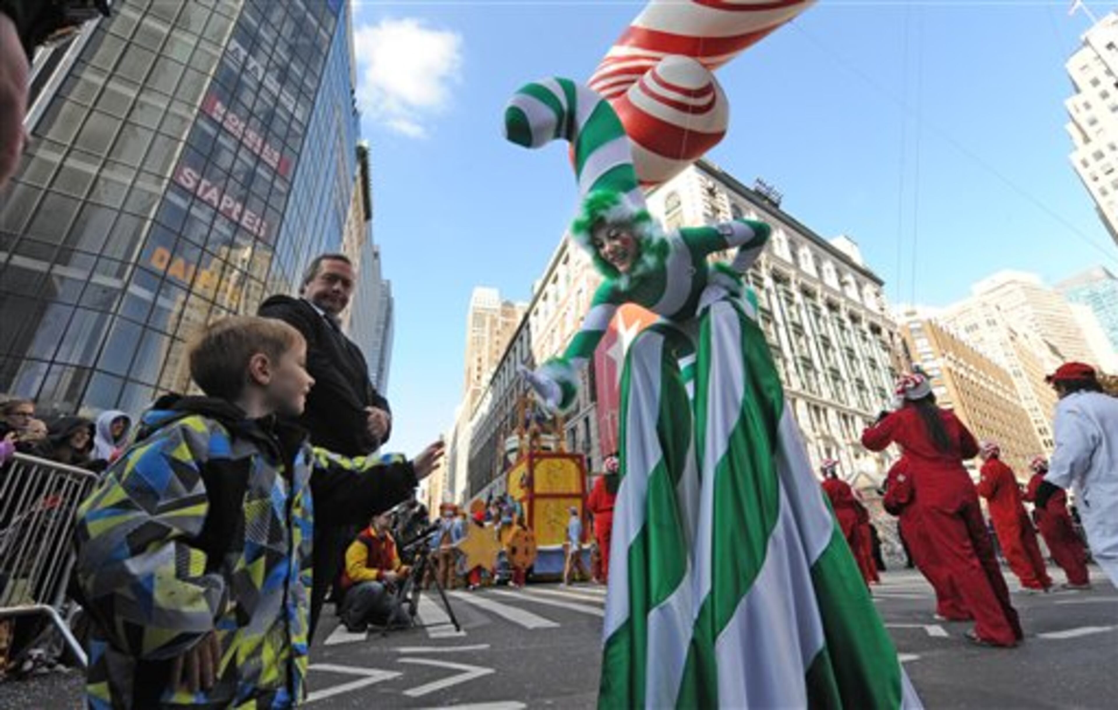 A Candy Cane girl reaches out to a child at Herald Square in celebration of the 86th annual Macy's Thanksgiving Day Parade,Thursday, Nov 22, 2012, in New York. The popular Macy's parade, attended by more than 3 million people and watched by 50 million on TV, included such giant balloons as Elf on a Shelf and Papa Smurf, a new version of Hello Kitty, Buzz Lightyear, Sailor Mickey Mouse and the Pillsbury Doughboy. (AP Photo/ Louis Lanzano)