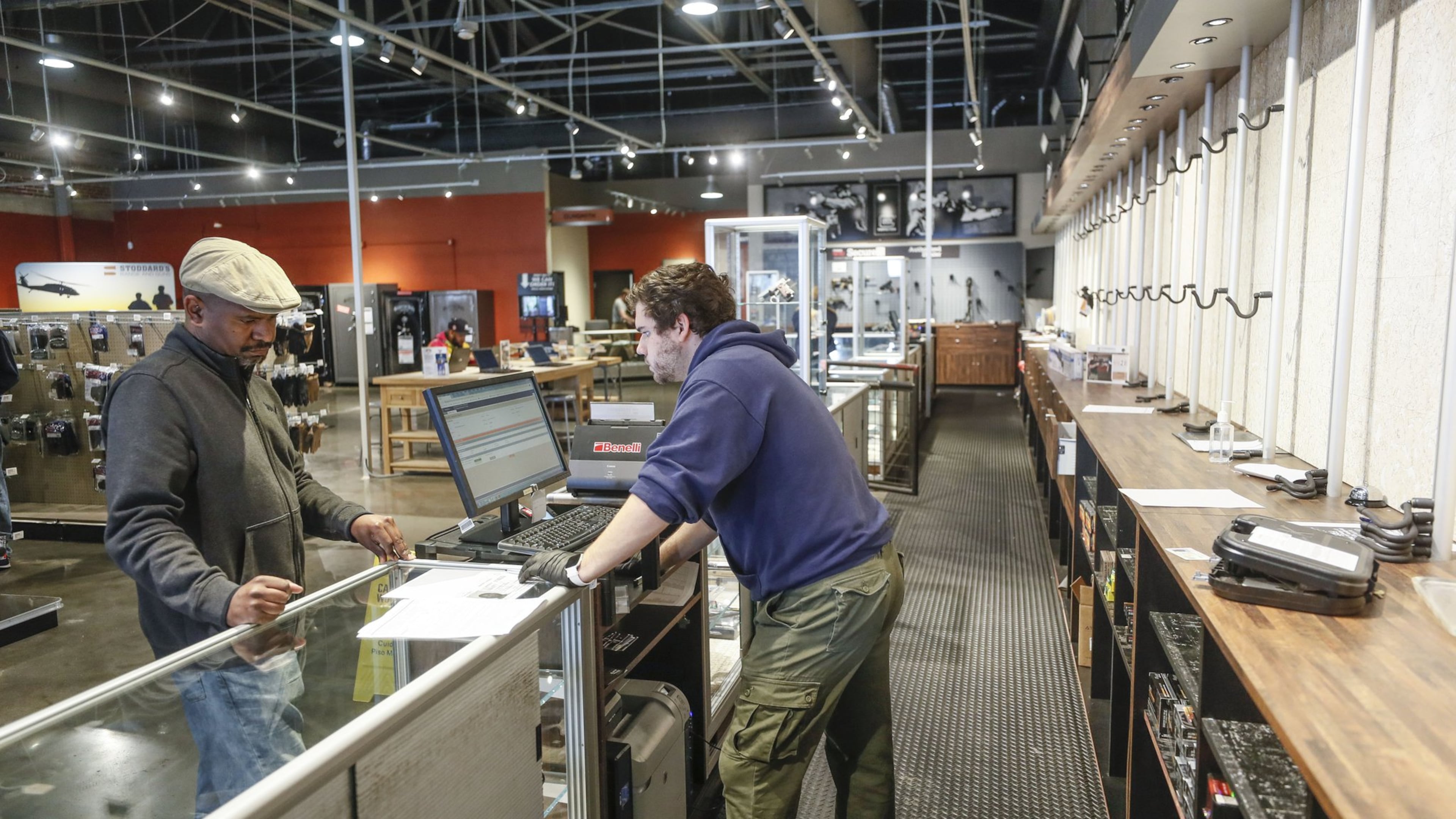 Grahame Grantham (center), a manager at Stoddard’s Range and Guns in Atlanta, in front of an empty display wall, helps a customer wanting to make a purchase. The store has seen an uptick in ammunition and gun sales as the coronavirus threat intensifies. Bob Andres / robert.andres@ajc.com