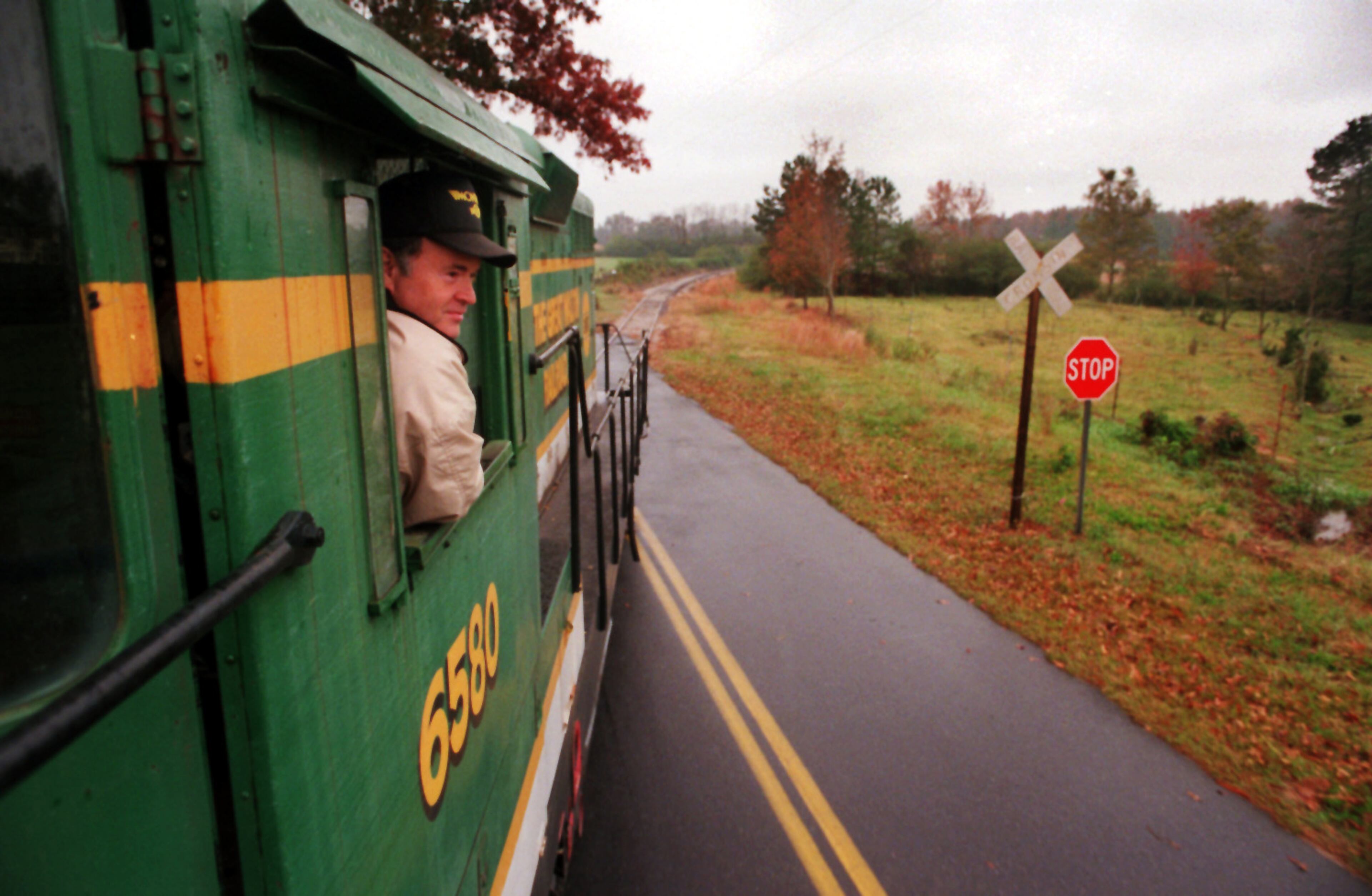 Engineer Wayne Holly, 52, watches for oncoming traffic as he makes a road crossing during a run from Social Circle to Monroe to pick up rail cars for the Great Walton Railroad on Tuesday, Nov. 7, 1995.