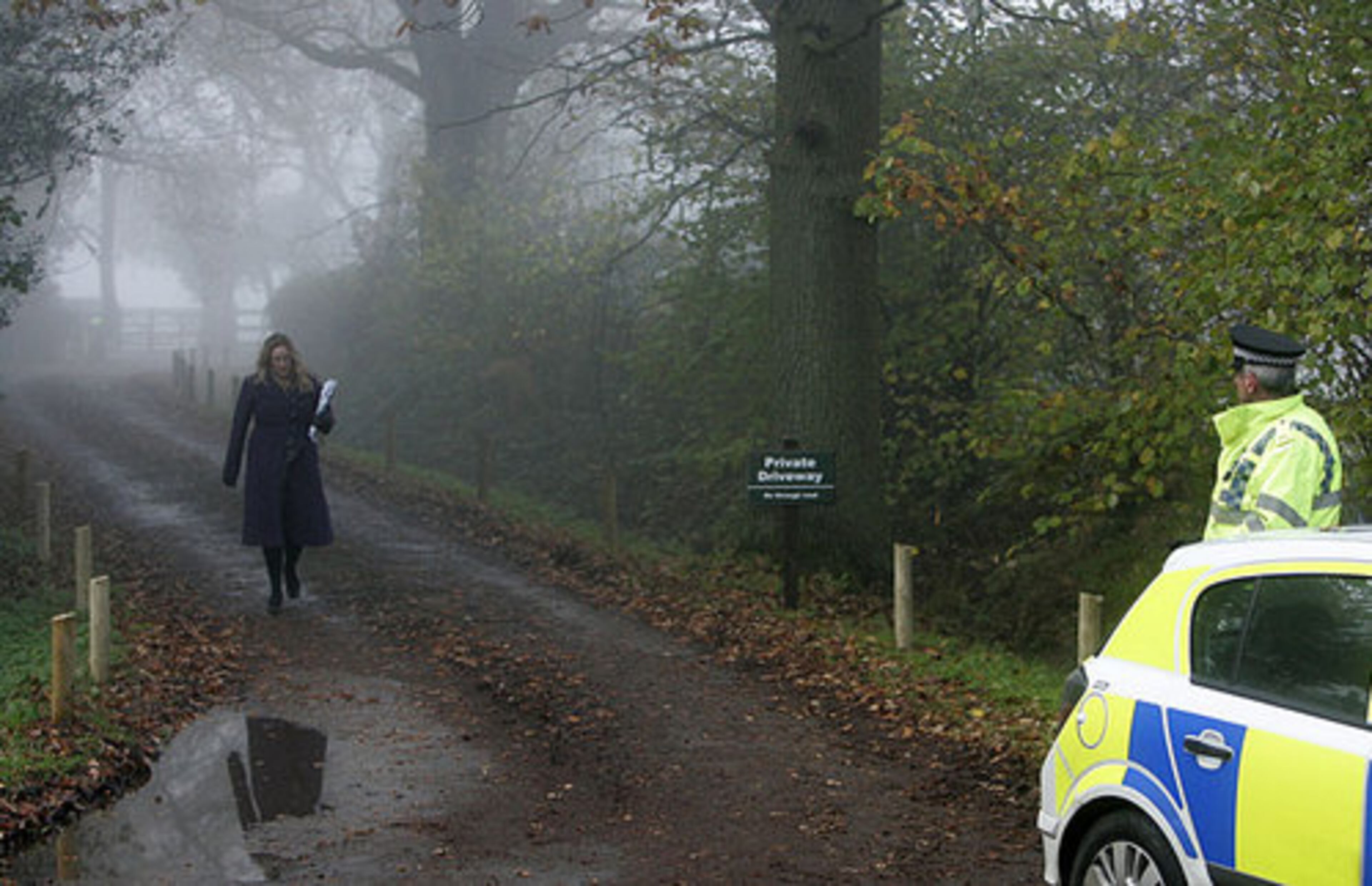 A police officer, right, stands guard as a press officer walks from the house of Kate Middleton's parents in Bucklebury, England, Tuesday, Nov. 16, 2010. Britain's Prince William, who is second in line to the throne, and girlfriend Kate Middleton are engaged and will marry next spring or summer in London.