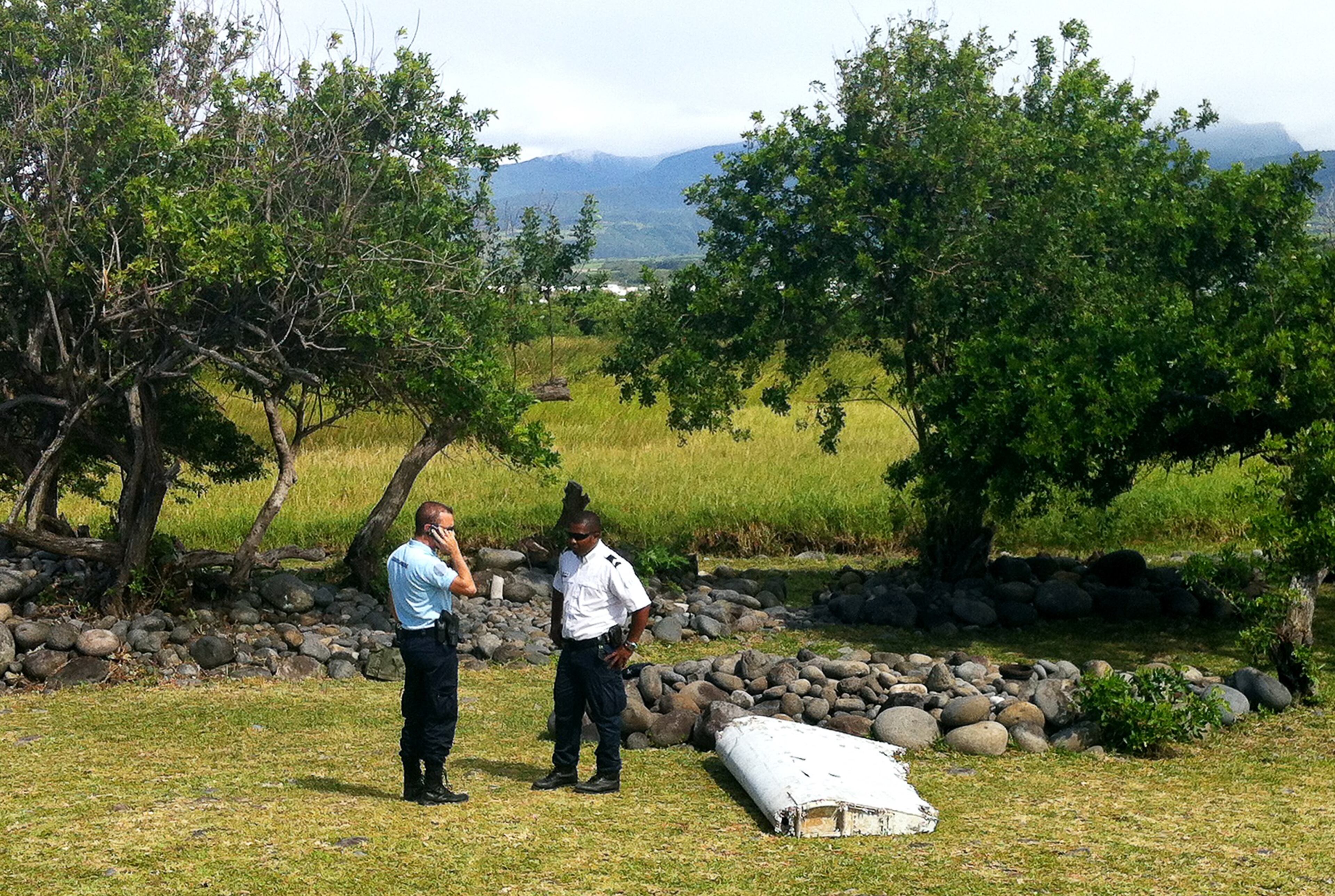 A policeman and a gendarme stand next to a piece of debris from an unidentified aircraft found in the coastal area of Saint-Andre de la Reunion, in the east of the French Indian Ocean island of La Reunion, on July 29, 2015. The two-metre-long debris, which appears to be a piece of a wing, was found by employees of an association cleaning the area and handed over to the air transport brigade of the French gendarmerie (BGTA), who have opened an investigation. An air safety expert did not exclude it could be a part of the Malaysia Airlines flight MH370, which went missing in the Indian Ocean on March 8, 2014. (Photo: YANNICK PITOU/AFP/Getty Images)