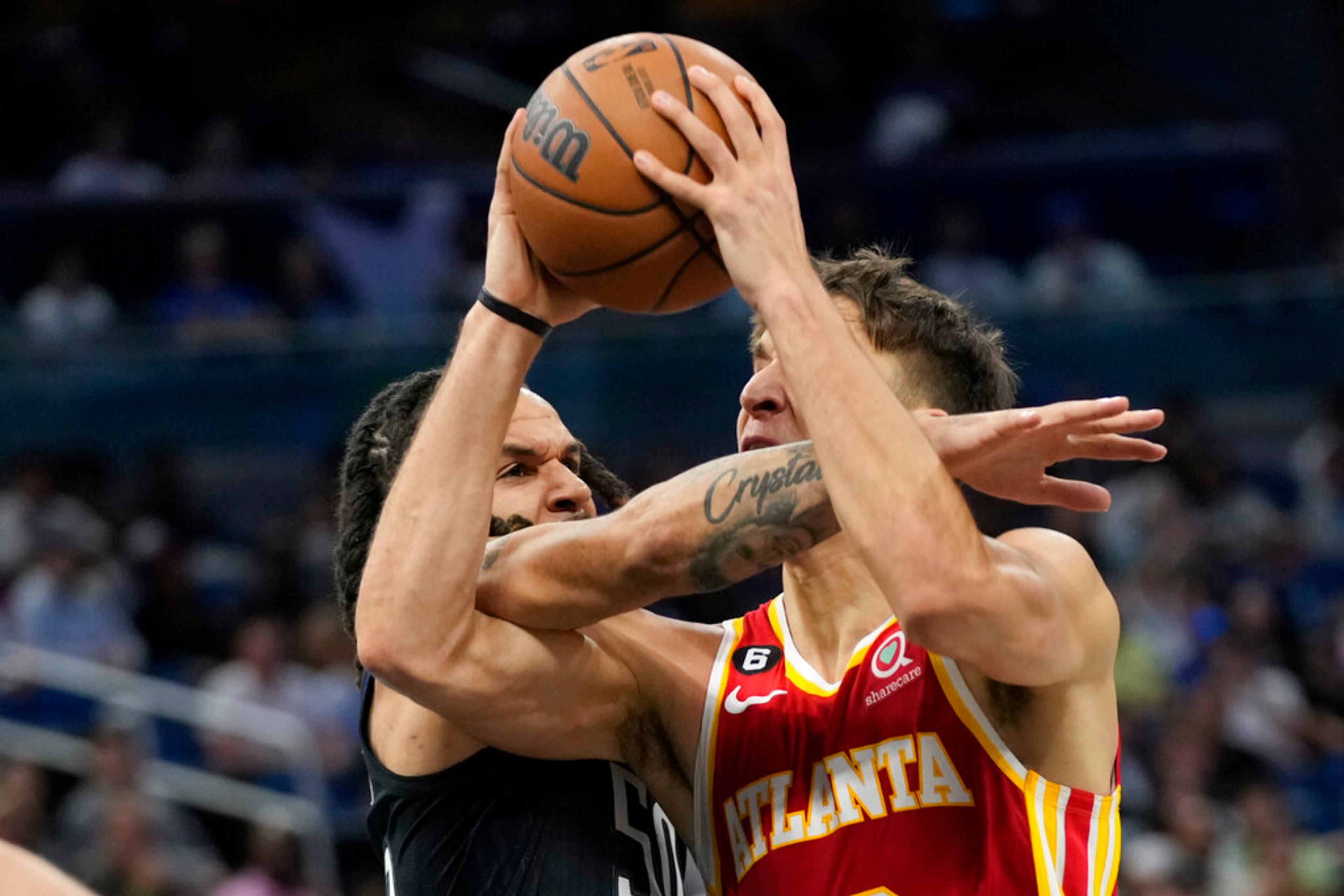 Orlando Magic's Cole Anthony, left, fouls Atlanta Hawks' Bogdan Bogdanovic as he goes in for a shot during the first half of an NBA basketball game, Wednesday, Dec. 14, 2022, in Orlando, Fla. (AP Photo/John Raoux)