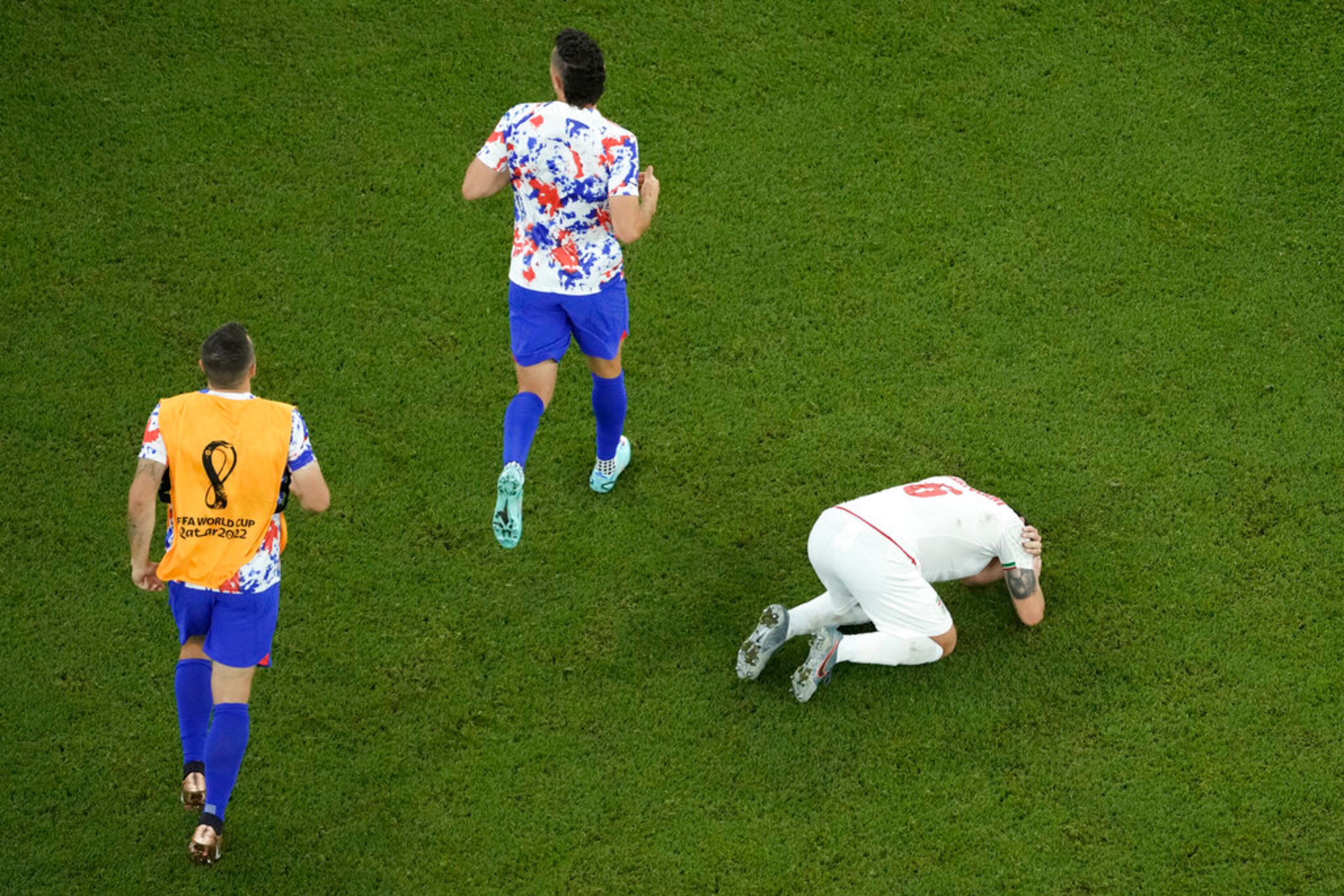 Iran's Saeid Ezatolahi, right, reacts while the players of the United States celebrate at the end of the World Cup group B soccer match between Iran and the United States at the Al Thumama Stadium in Doha, Qatar, Wednesday, Nov. 30, 2022. The United States won 1-0 to the advance in the tournament. (AP Photo/Hassan Ammar)