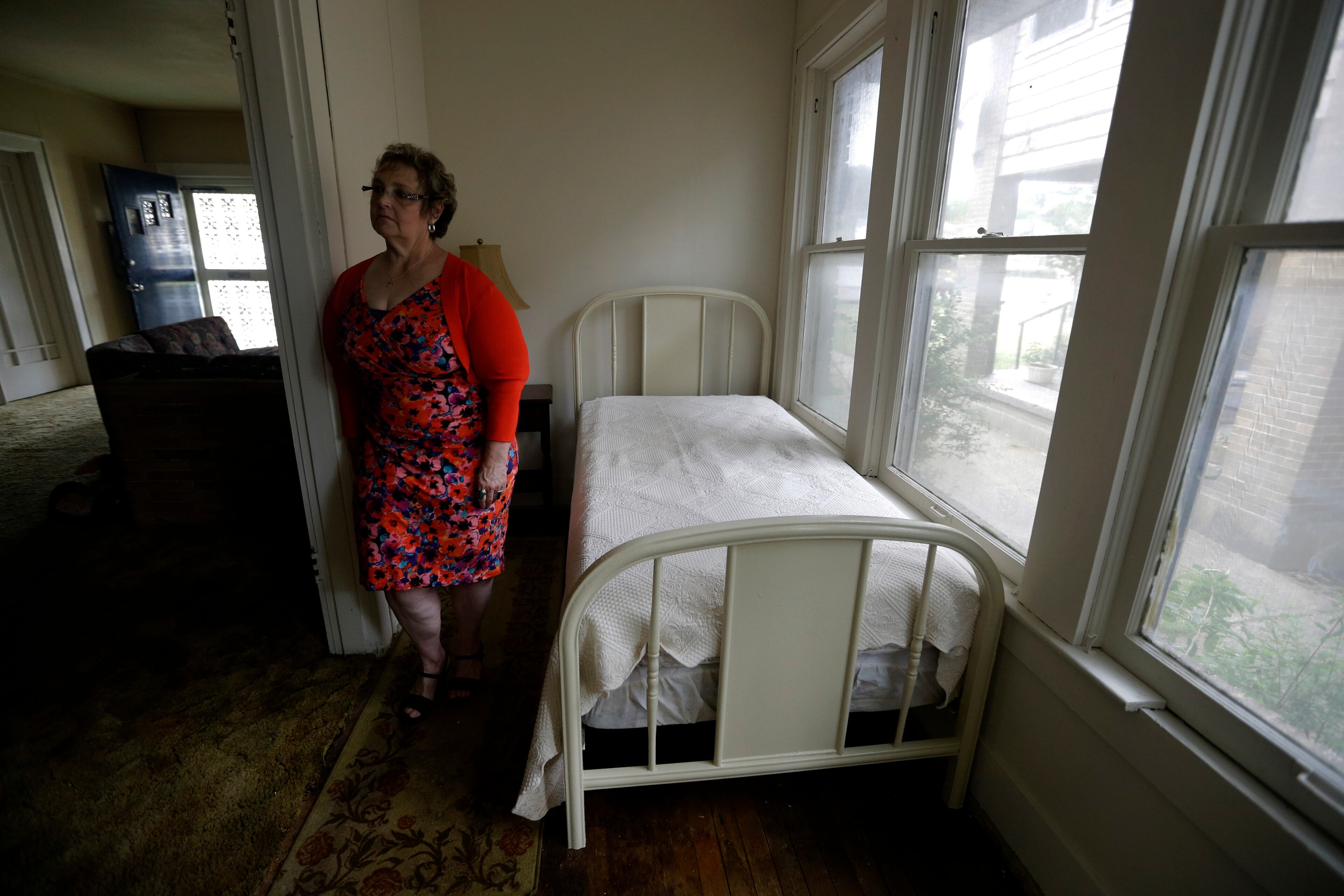 In this 2013 file photo, Patricia Hall stands for a photograph in the 5-by-14' room that Lee Harvey Oswald rented in 1963 at her family's rooming house in Dallas. Oswald stayed at the red brick house with white trim during the week while working his new job at the Texas School Book Depository, and on the weekends he returned to the suburb of Irving where his wife lived. Hall said she's been considering selling the house for years, but decided the time was right as this year marks the 50th anniversary of Kennedy's assassination in downtown Dallas. (AP Photo/Tony Gutierrez)