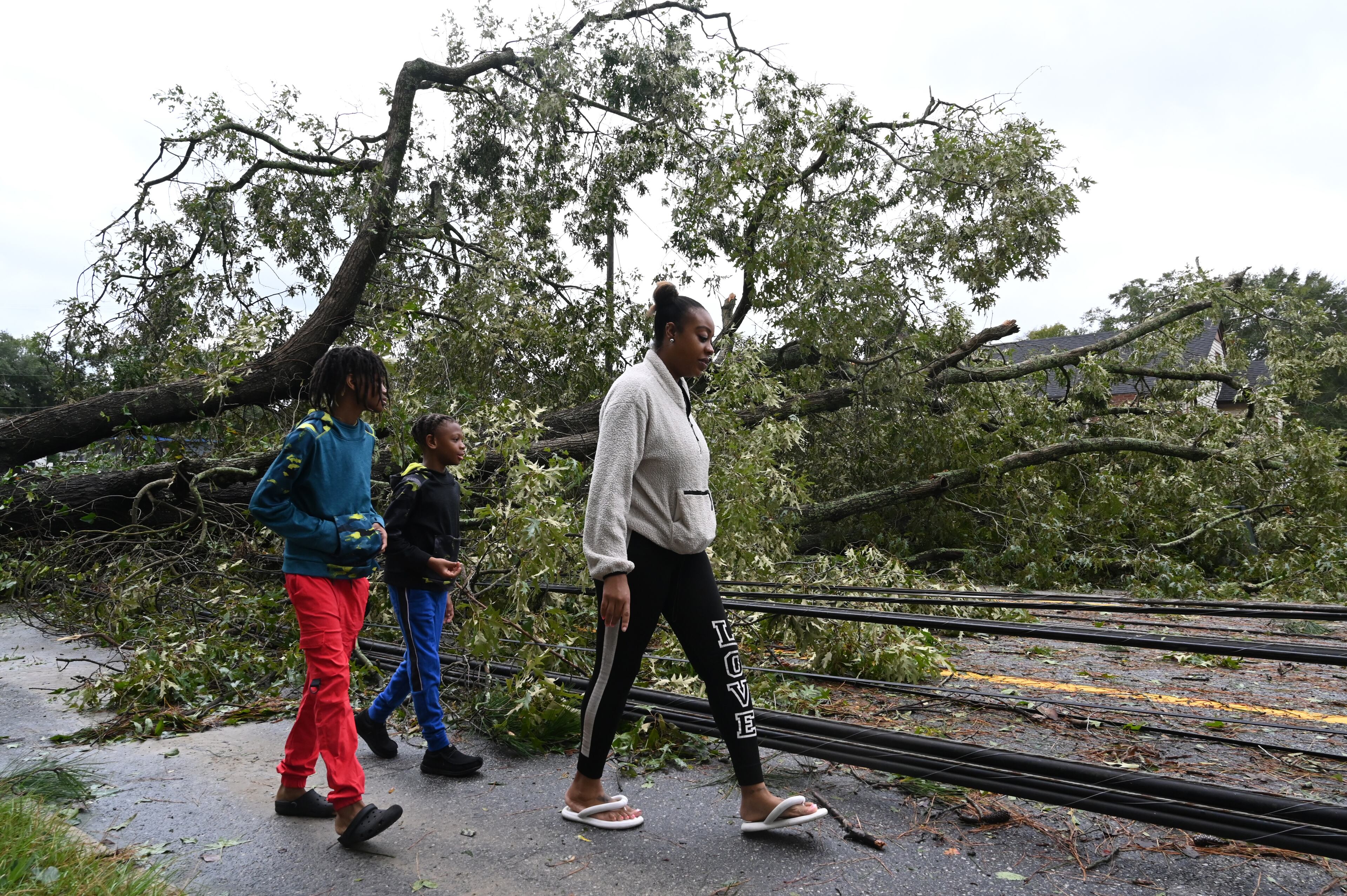 Angel Coney with her two sons Travi (left), 10, and Mari, 9, check out fallen trees and wires caused by Hurricane Helene in front of their house, Friday, September 27, 2024 in Dublin. Fast-moving Helene, which entered Georgia as a Category 2 hurricane Friday morning, continues its powerful march toward metro Atlanta. The storm, which made landfall as a Category 4 in Florida’s Big Bend region Thursday night with maximum sustained winds of 140 mph, continues to pack a dangerous punch and is responsible for at least three deaths in Georgia. Helene’s sustained winds are now at 70 mph, making it a tropical storm status, and it is quickly traveling north. (Hyosub Shin / AJC)