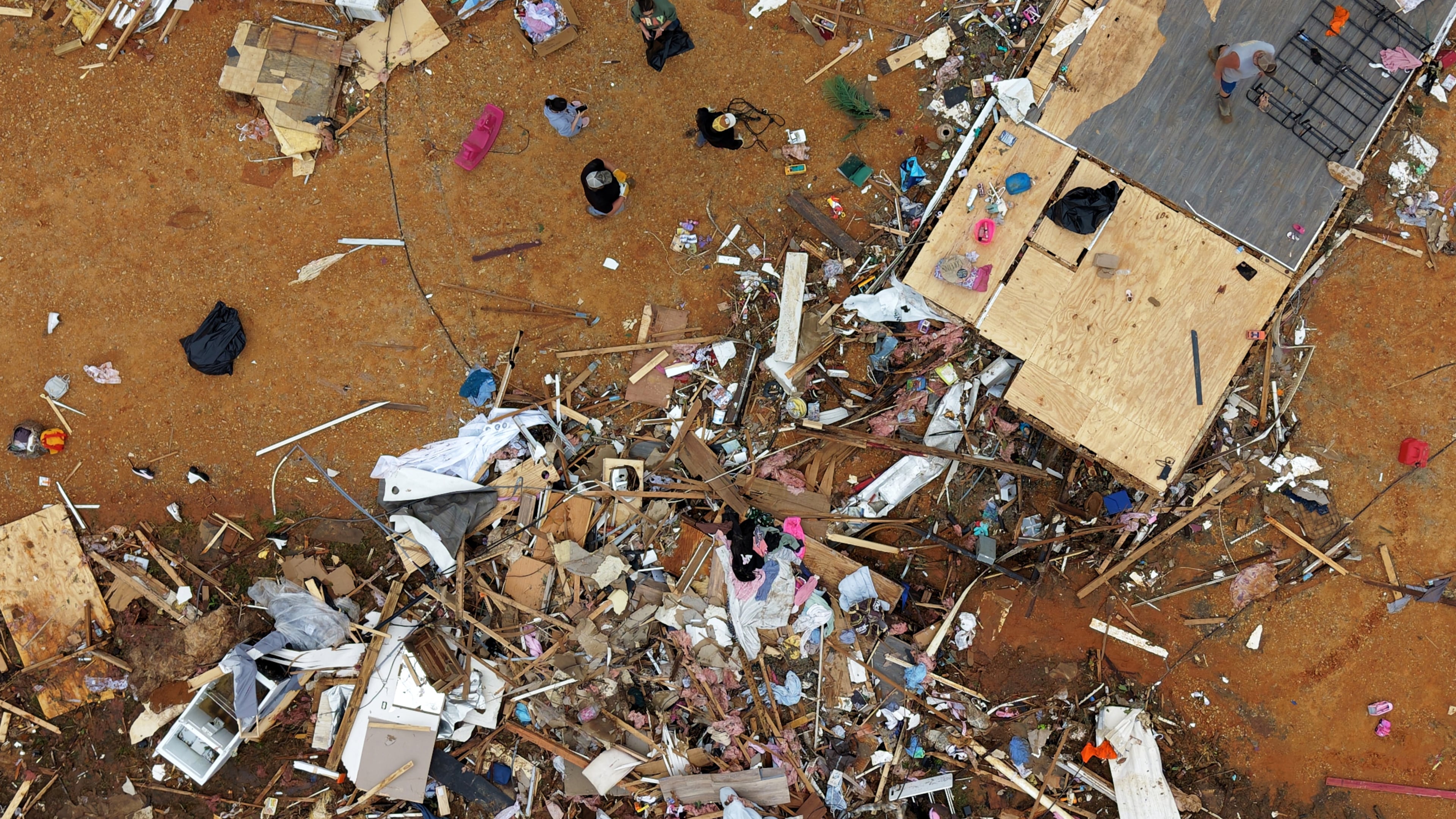 People walk among debris at Gene's Mobile Home Supply, a trailer park in Bogue Chitto, Miss., Thursday, May, 7, 2026, after a tornado cut across the state. (AP Photo/Gerald Herbert)