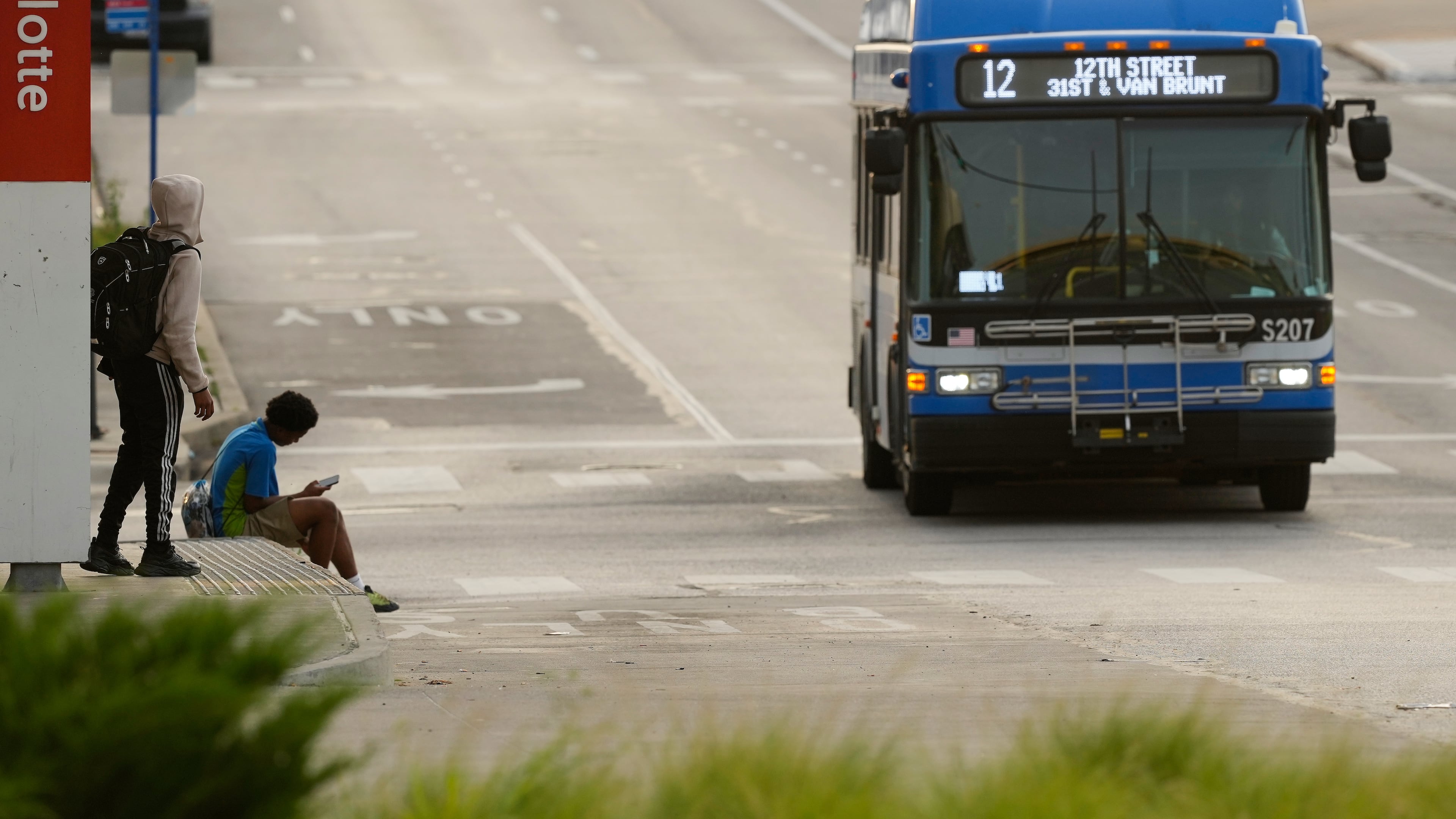 People wait for the bus at a transit center Friday, June 5, 2026, in Kansas City, Mo. (AP Photo/Charlie Riedel)