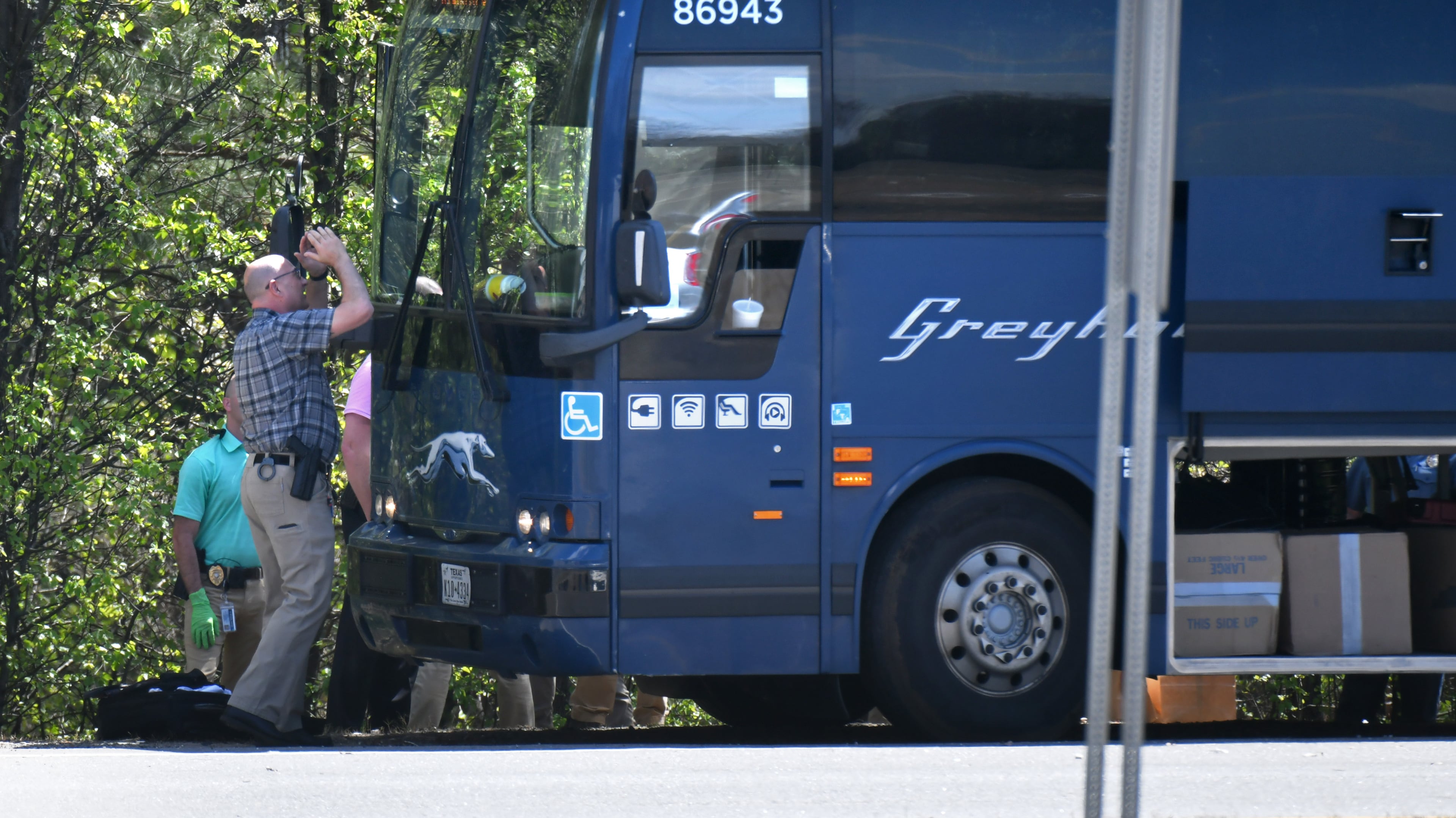 An officer tries to look inside a Greyhound bus through the windshield after an armed man was taken into custody on an I-85 on-ramp in Gwinnett County on Tuesday.