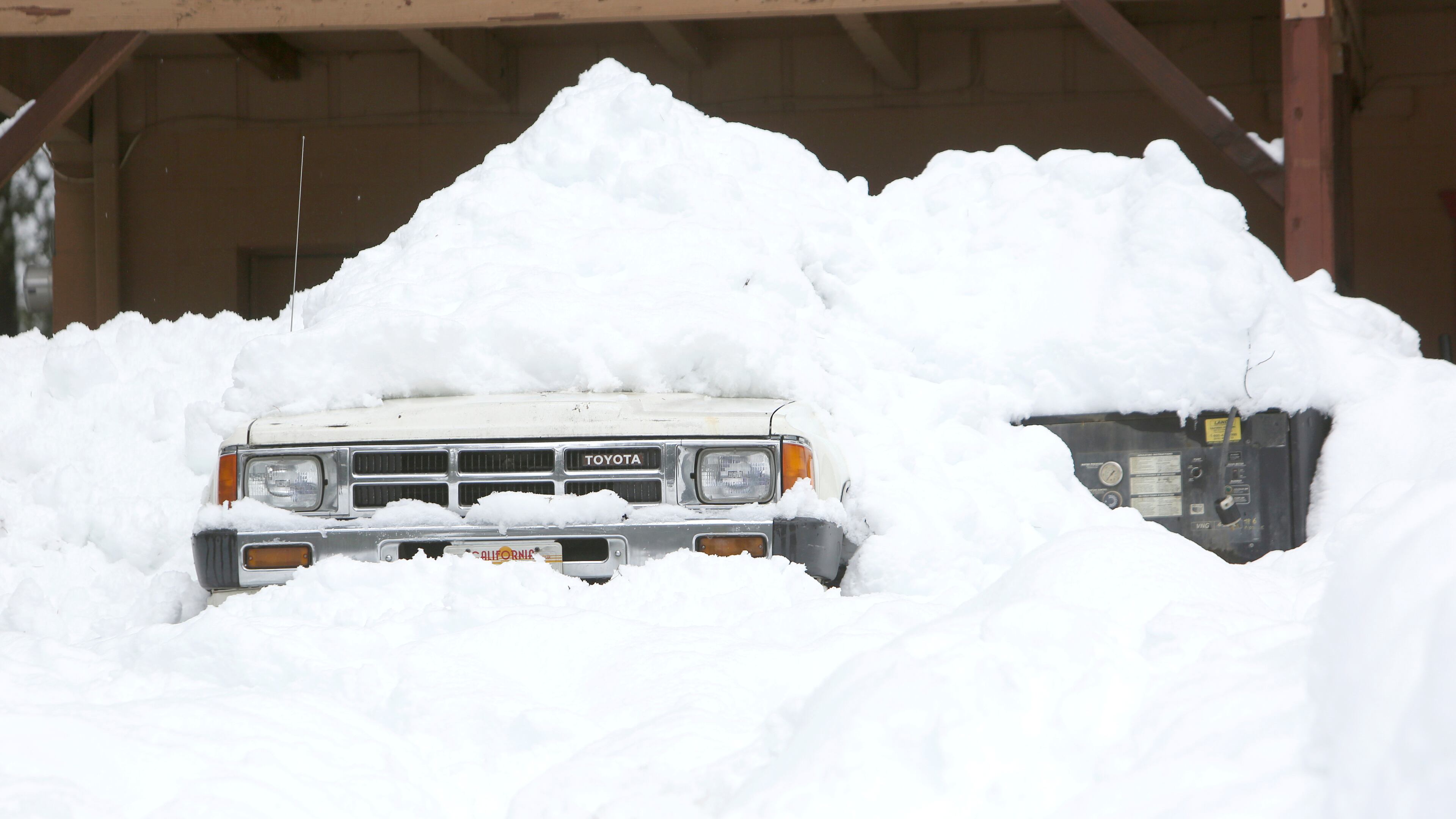 A pickup is almost covered in snow in front of this home in Nevada City, California.