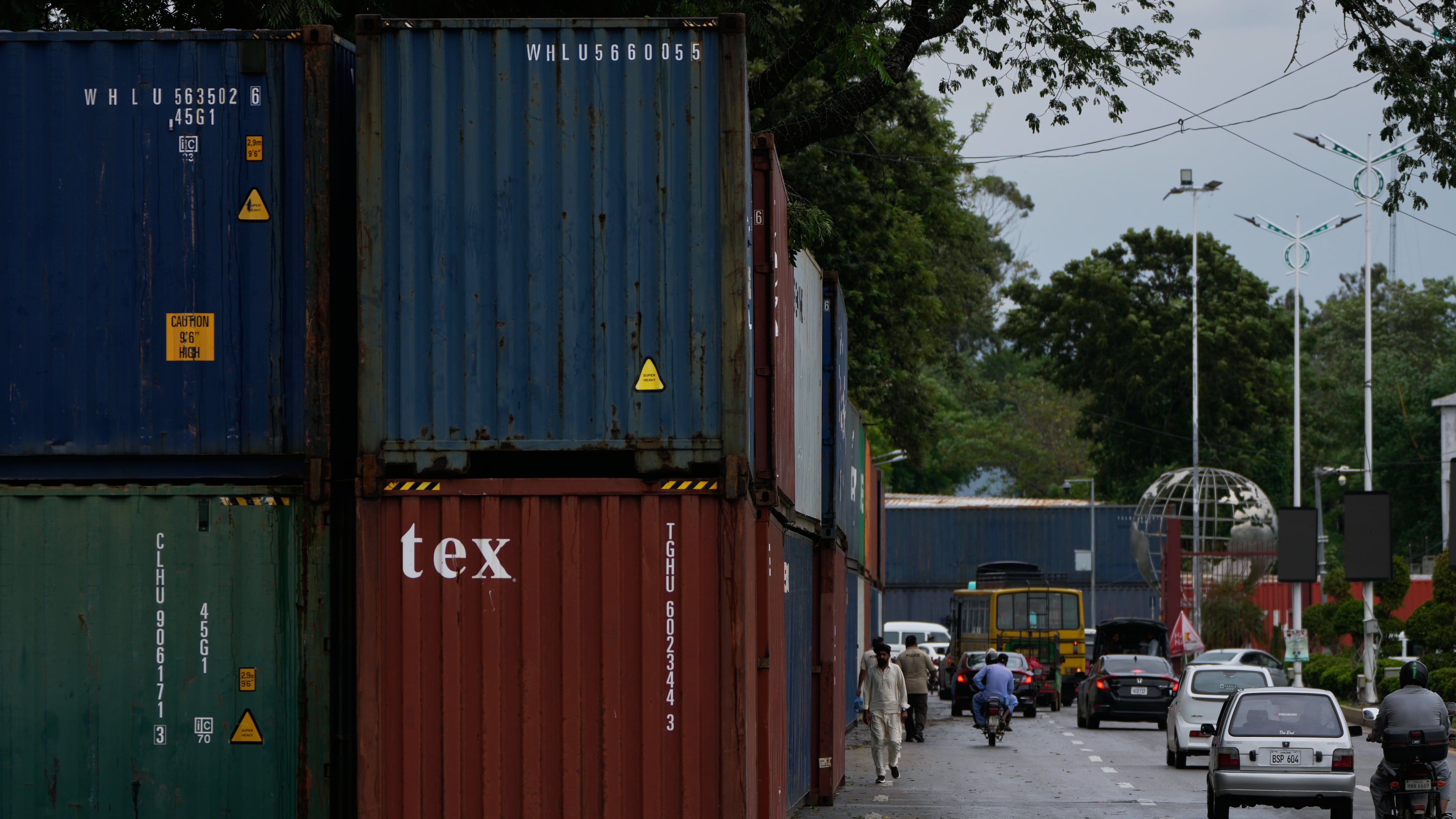 Vehicles drive past shipping containers placed by authorities to seal off an area ahead of a plan protest march by the supporters of imprisoned former Prime Minister Imran Khan demanding his release, in Islamabad, Pakistan, Monday, Sept. 28, 2026. (AP Photo/Anjum Naveed)