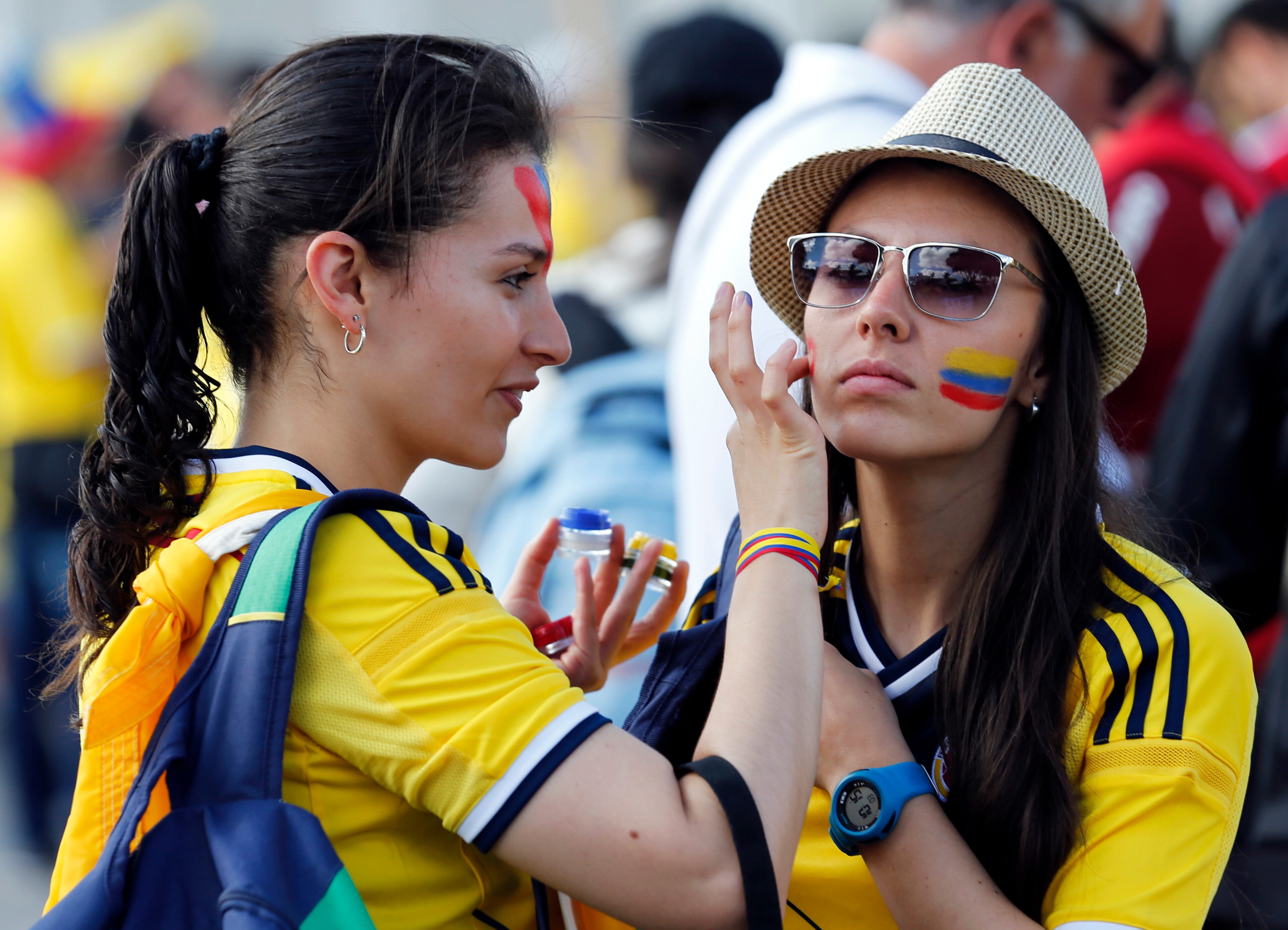 Colombian supporters apply face paint in the colors of their national flag ahead of the start of the group C World Cup soccer match between Colombia and Greece at the Mineirao Stadium in Belo Horizonte, Brazil, Saturday, June 14, 2014. (AP Photo/Jon Super)