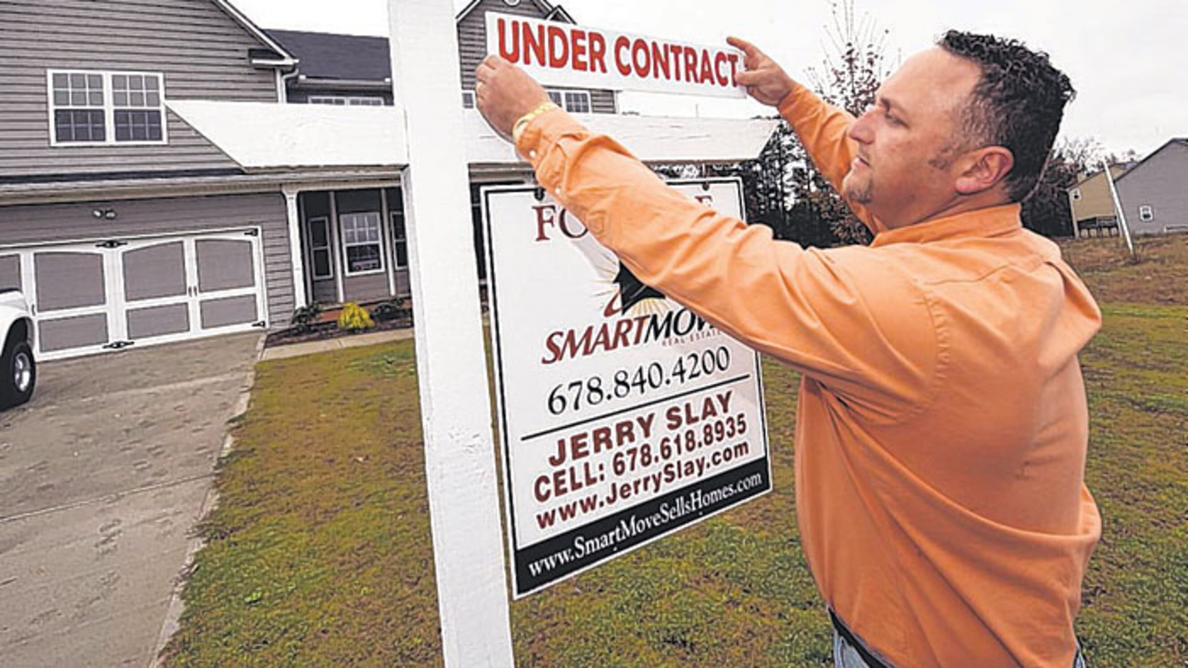 Real estate agent Jerry Slay places an “Under Contract” sign at a house in Douglas County. Many bank-owned homes are selling, fueled by a demand from first-time home buyers.