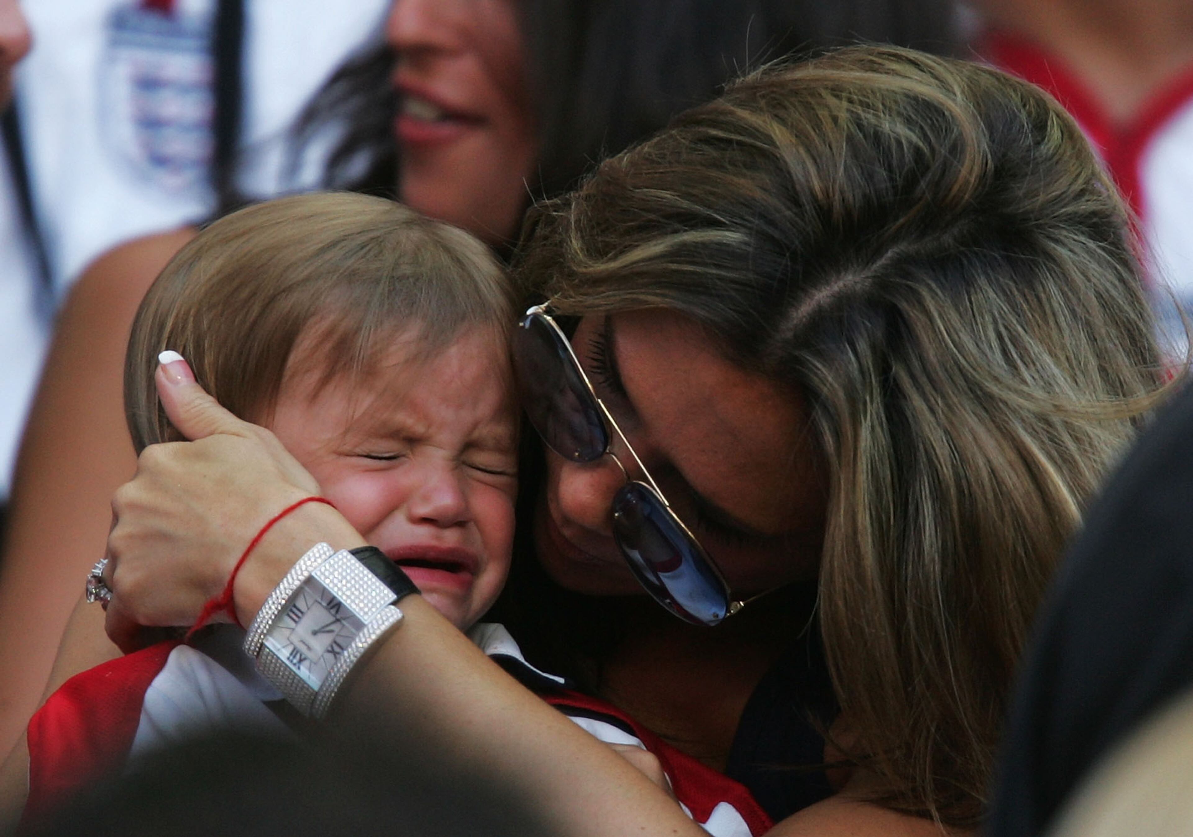 Romeo Beckham is consoled by his mum Victoria Beckham during the France v England Group B match in the 2004 UEFA European Football Championships at the Estadio da Luz on June 13, 2004 in Lisbon, Portugal. (Photo by Ross Kinnaird/Getty Images)