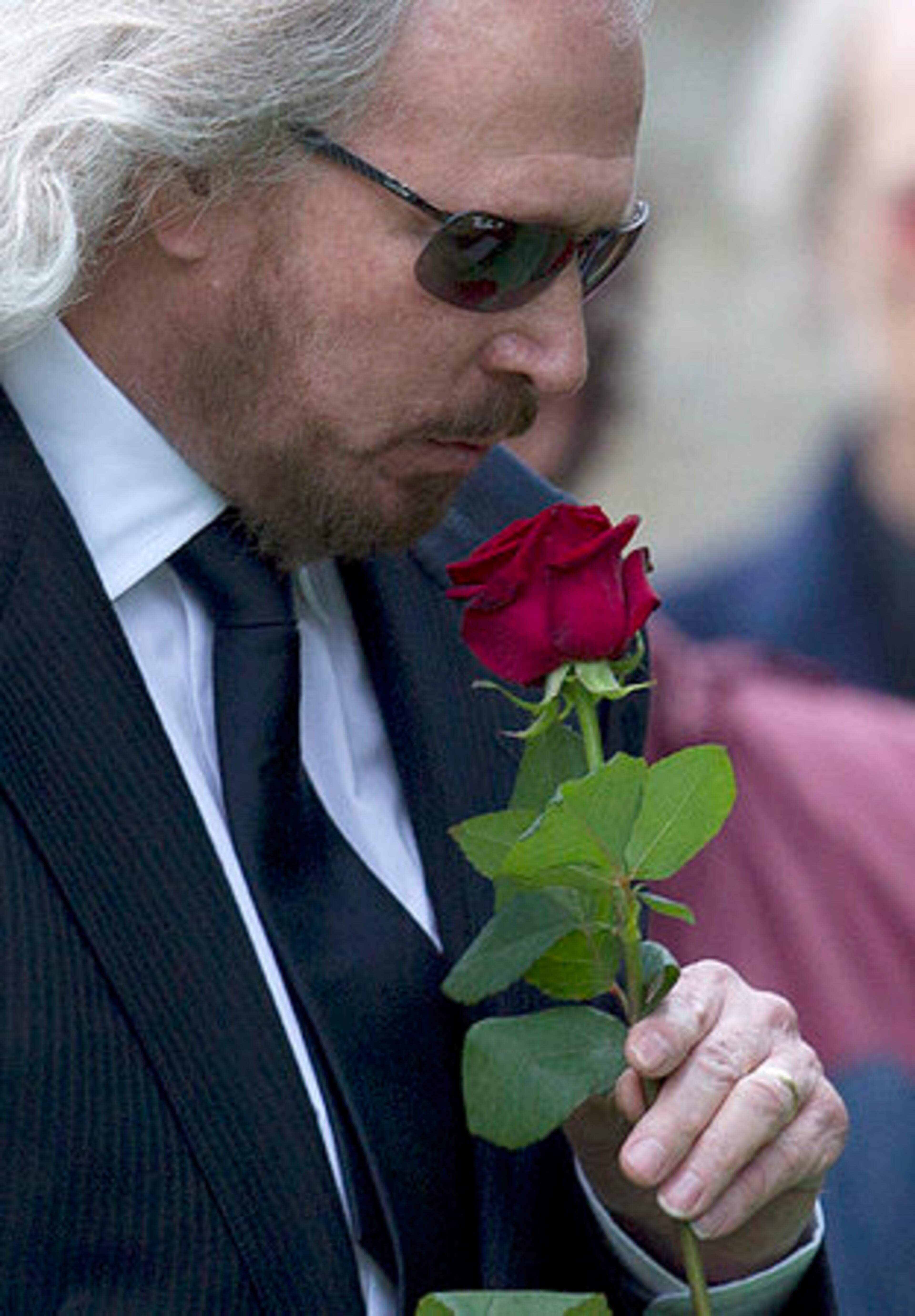 Barry Gibb kisses a rose in farewell to his brother Robin Gibb at the graveside at St Mary's Church in Thame, England, Friday, June 8, 2012. Robin Gibb a member of the iconic Bee Gees pop group died May 20, after a long battle with cancer.