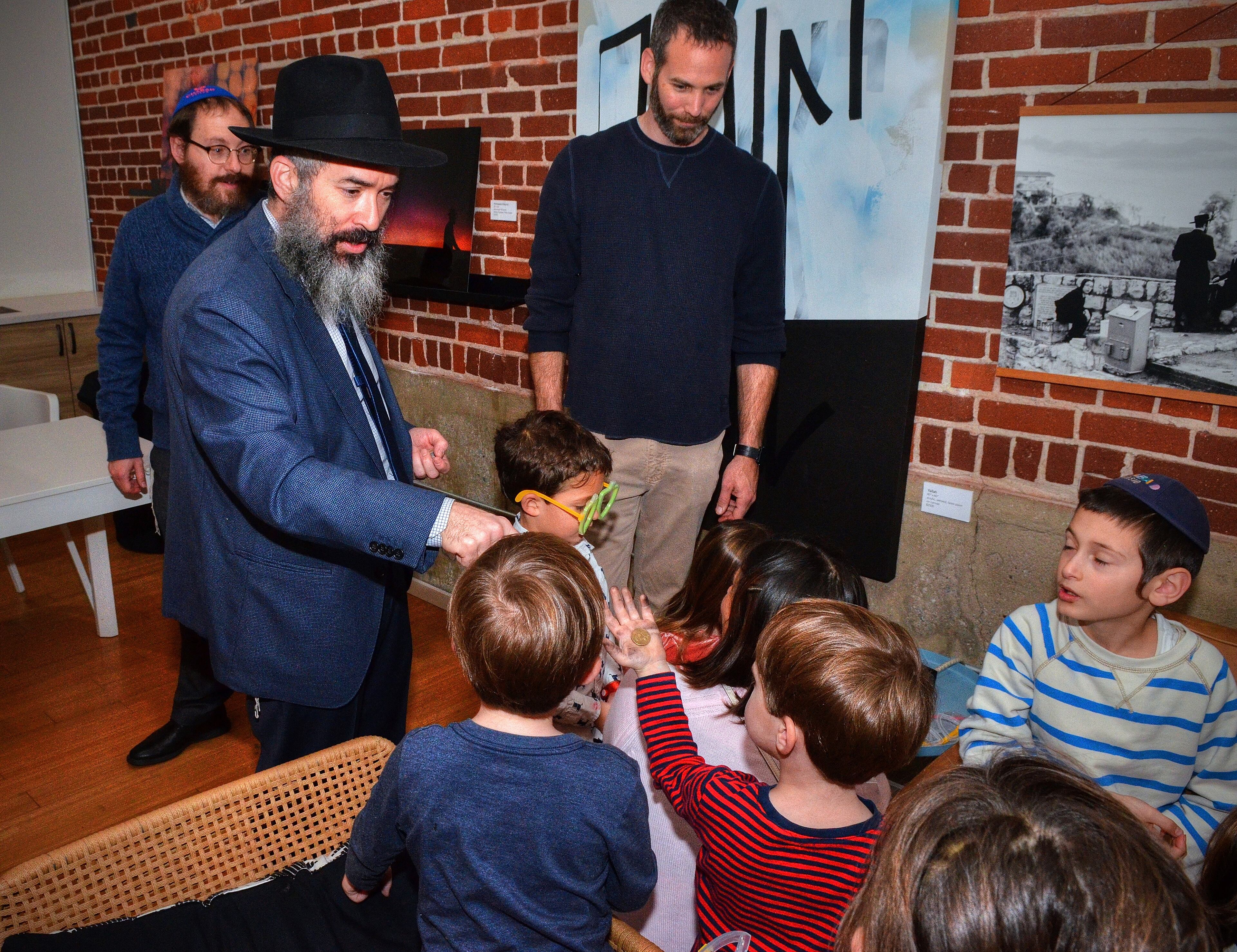 191222 Atlanta, Ga: By tradition, Rabbi Eliyahu Schusterman gives out Gelt (Hanukkah money) to children after the menorah lighting celebration. Menorah lighting and celebration sponsored by Chabad Intown and MJCAA Day Camps. Music, entertainment, Dreidels, doughnuts, hot latkes, gelt drop and more. Children who RSVP will recieve and Chanukah gift. All photos taken Sunday 12/22/2019 at Chabad Intown, along the Beltline in Atlanta, Ga. (Photo credit Chris Hunt Photography) for 122319hanukkah