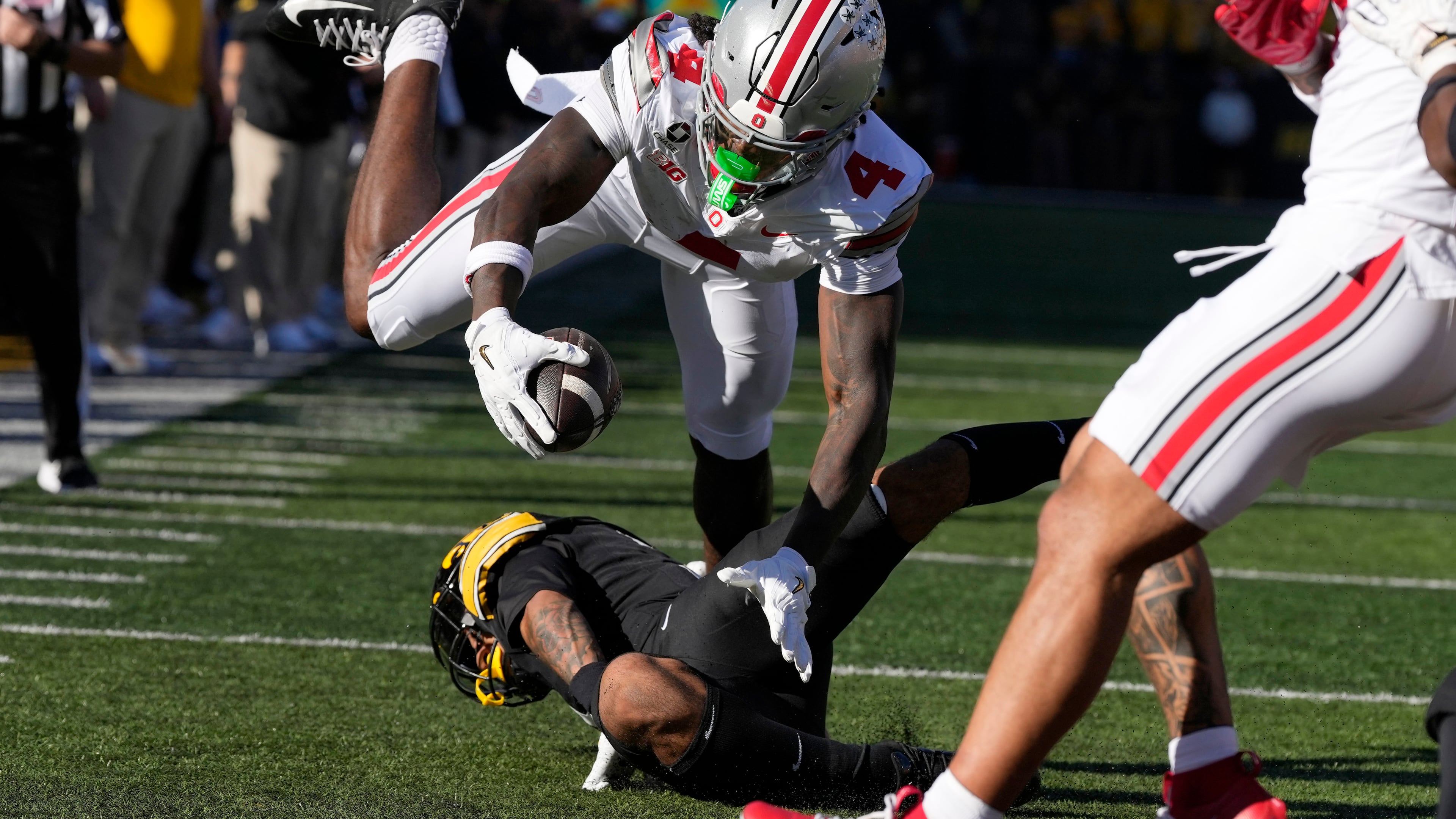 Ohio State wide receiver Jeremiah Smith (4) dives for a touchdown over Iowa defensive back Jaylen Watson during the first half of an NCAA college football game, Saturday, Oct. 3, 2026, in Iowa City, Iowa. (AP Photo/Charlie Neibergall)