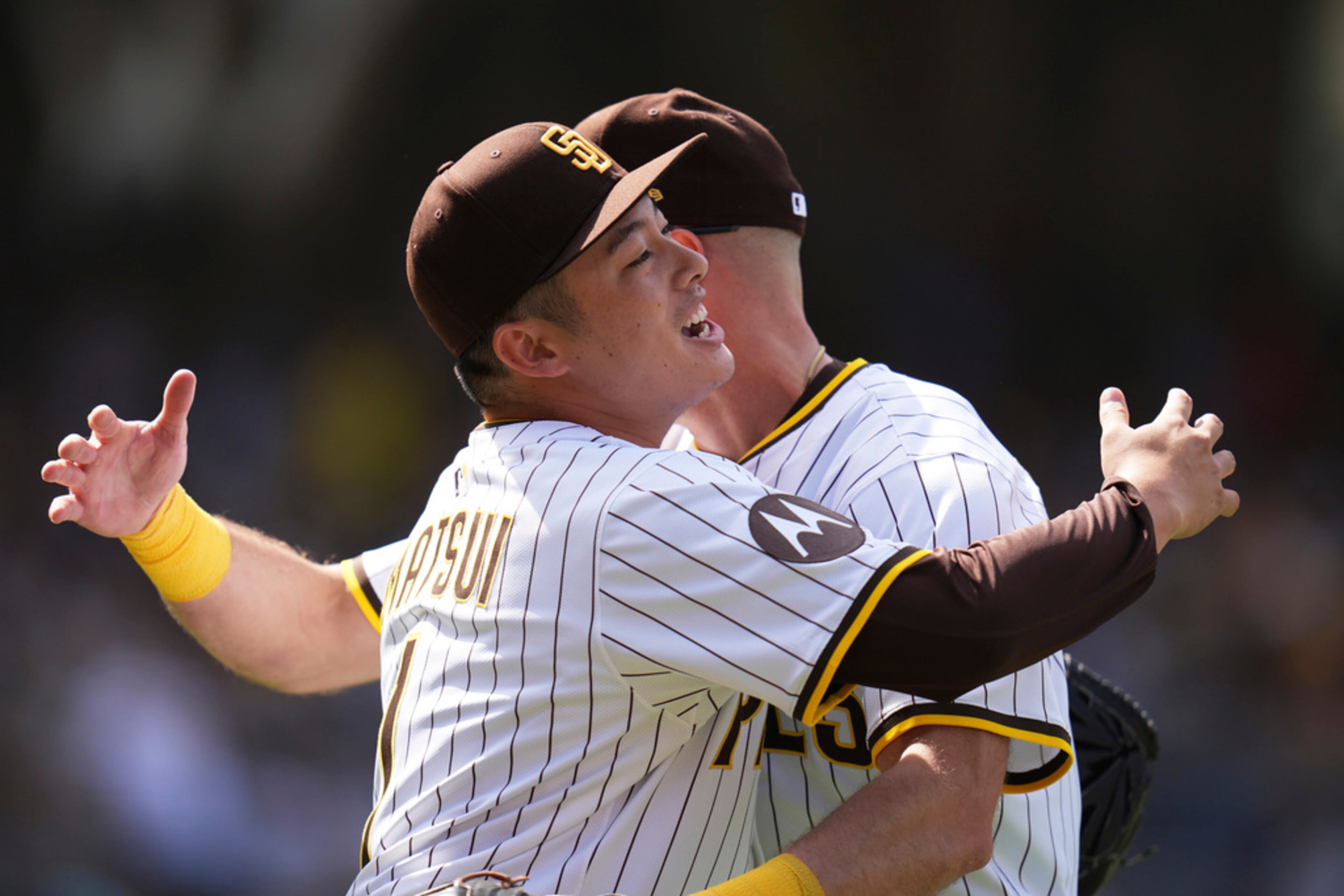 San Diego Padres relief pitcher Yuki Matsui, front, hugs right fielder Brandon Lockridge after Lockridge made a catch at the wall to end the top of the fourth inning of an opening-day baseball game against the Atlanta Braves, Thursday, March 27, 2025, in San Diego. (AP Photo/Gregory Bull)