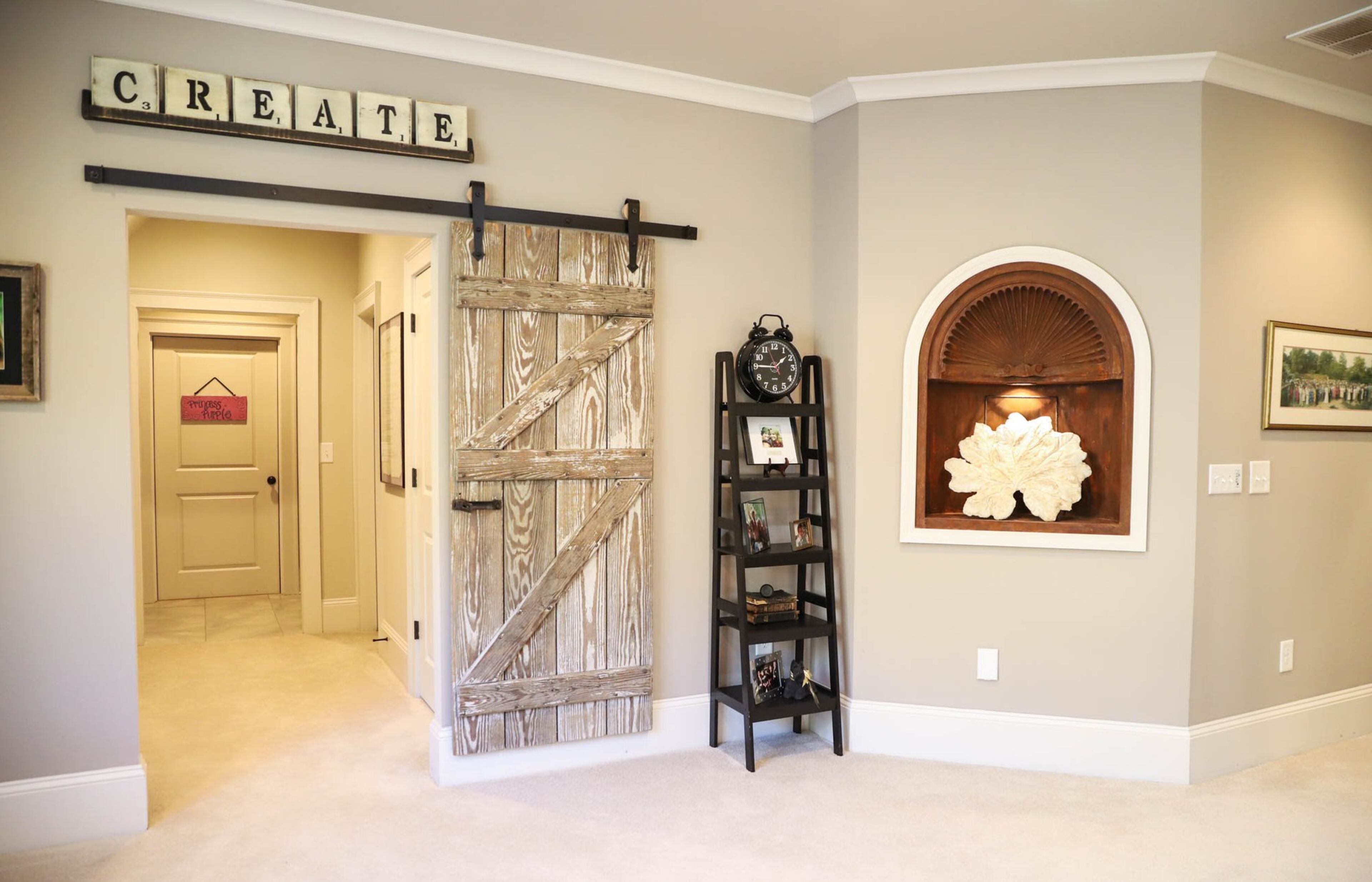 In Susan Graveline’s home office, she has a small wooden alcove that she had painted a faux rust finish by Patricia Presto of On the Surface. In that niche she has a large plaster leaf that she purchased from a local artist at Scott Antique Markets. Another unique barn door adds rustic elegance to the space. Text by Shannon Dominy. Photo by Reynolds Rogers.