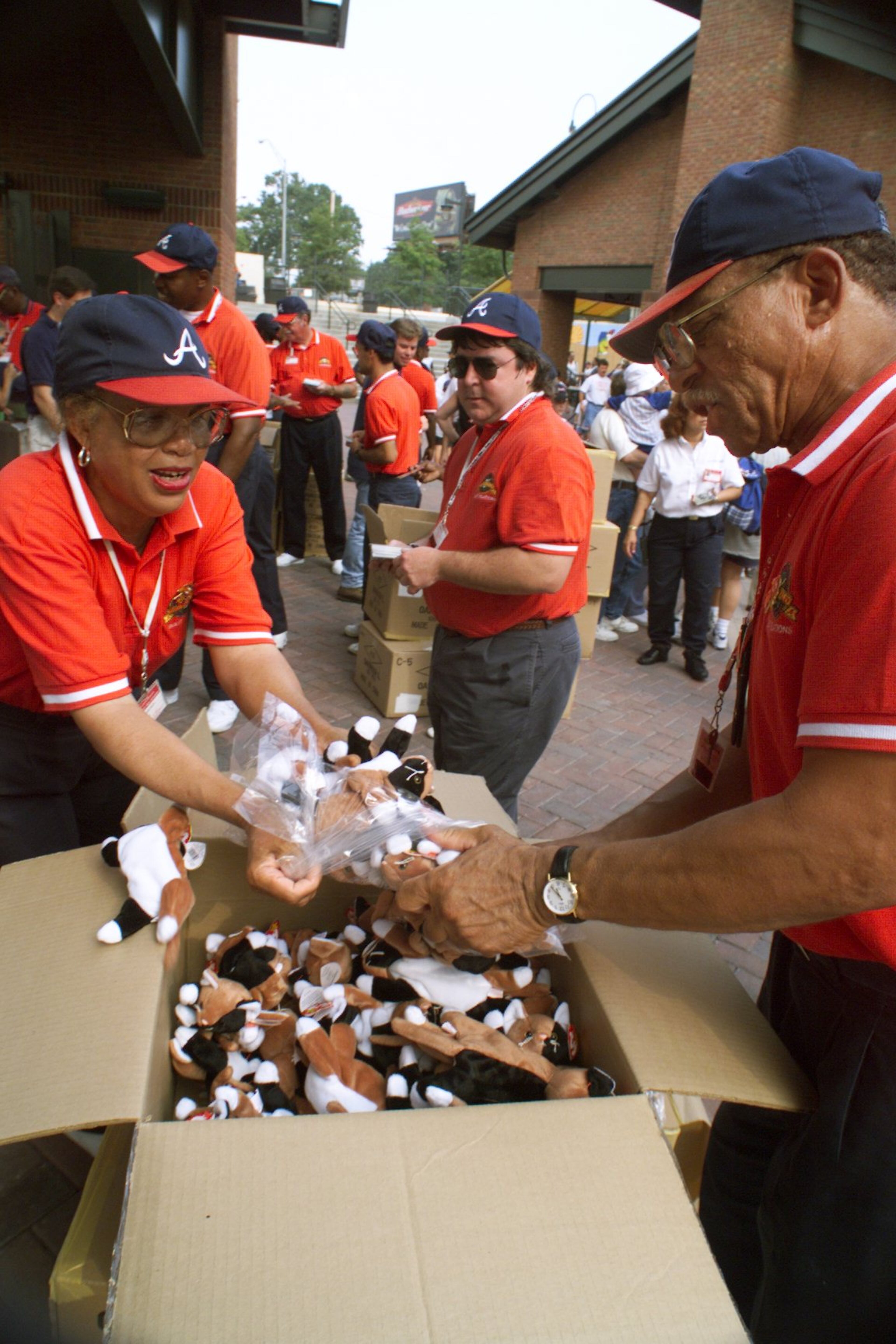 980819 ATLANTA: Braves' employees Cleophas Atwater (R,cq) and Bernice White (L,cq) rip open 'Chip the Cat' Beanie Baby boxes as fast as they can at the Turner Field Plaza gates, which opened early in anticipation of the Beanie Baby frenzy, during the BellSouth event Wednesday, Aug. 19, 1998 before the Giants game. (DAVID TULIS/AJC Staff)