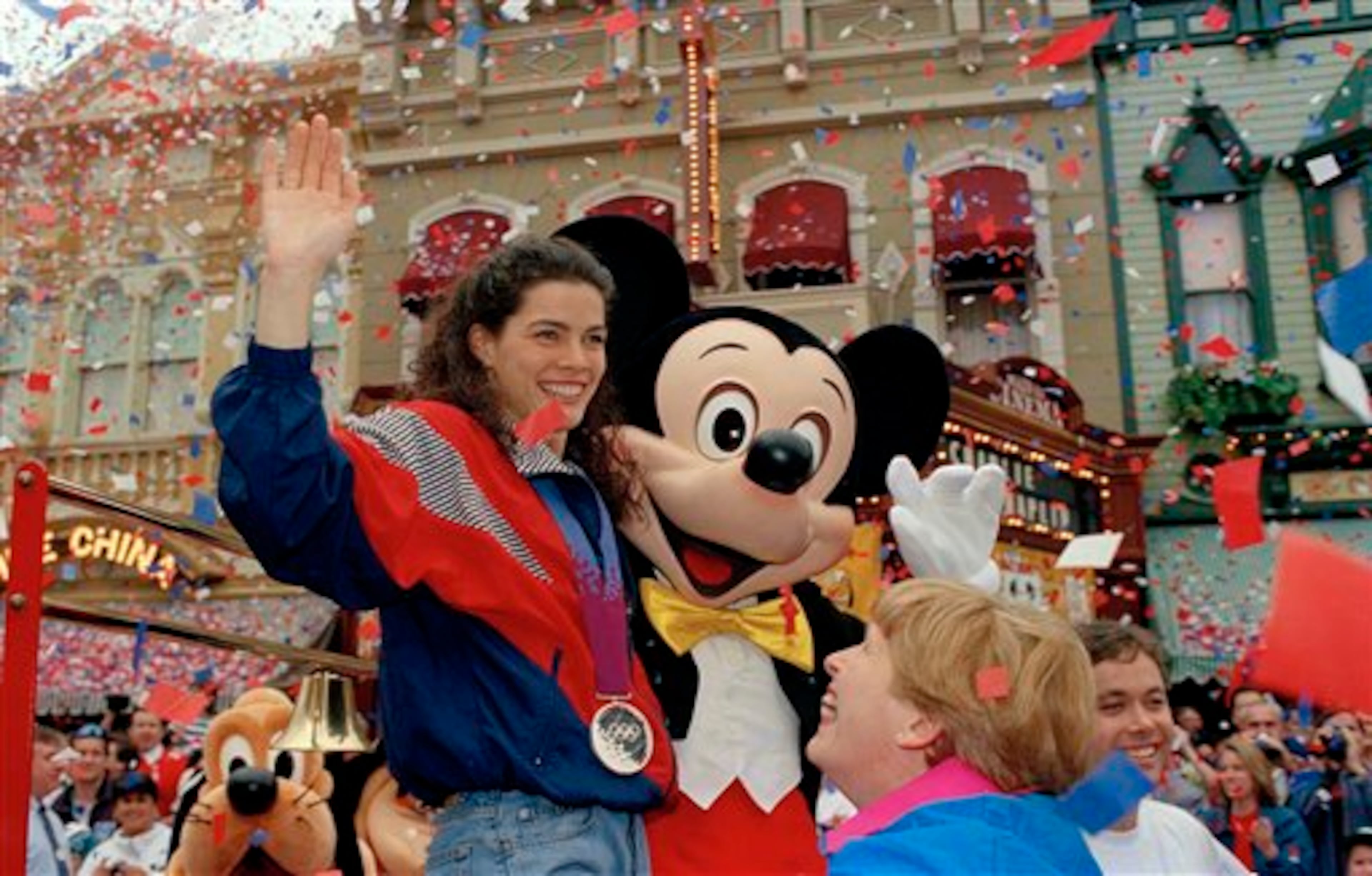 Olympic silver medalist Nancy Kerrigan rides down Main Street wearing her silver medal around her neck, at Disney World in Lake Buena Vista, Fla., Feb. 27, 1994. Mickey Mouse and Nancy's mother Brenda, right, ride along through the ticker tape parade. (AP Photo/Peter Cosgrove)