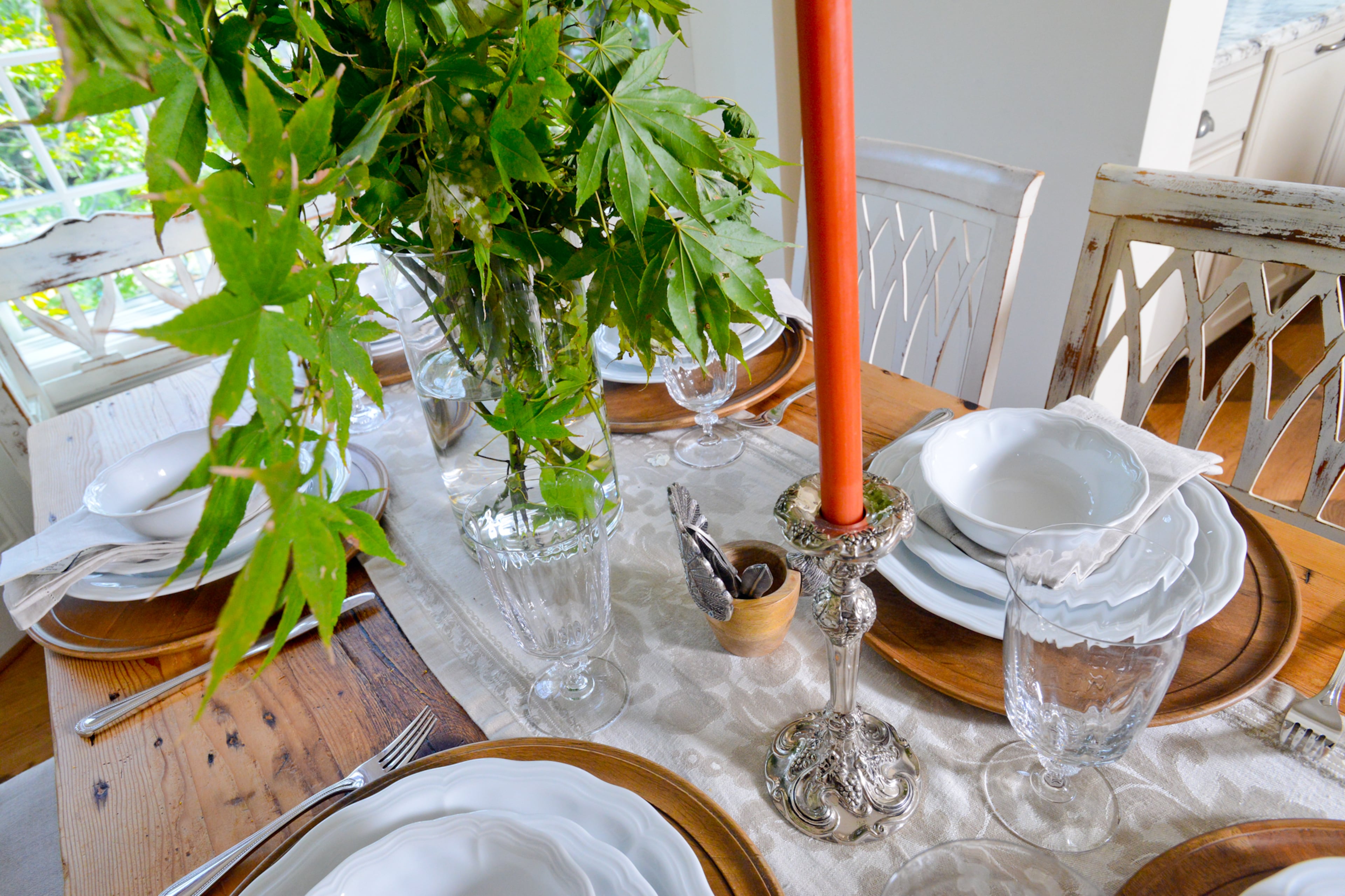 A table setting of wood chargers and white plates amid bouquets of greenery add to the fresh feel of the renovated 110-year-old East Lake home.