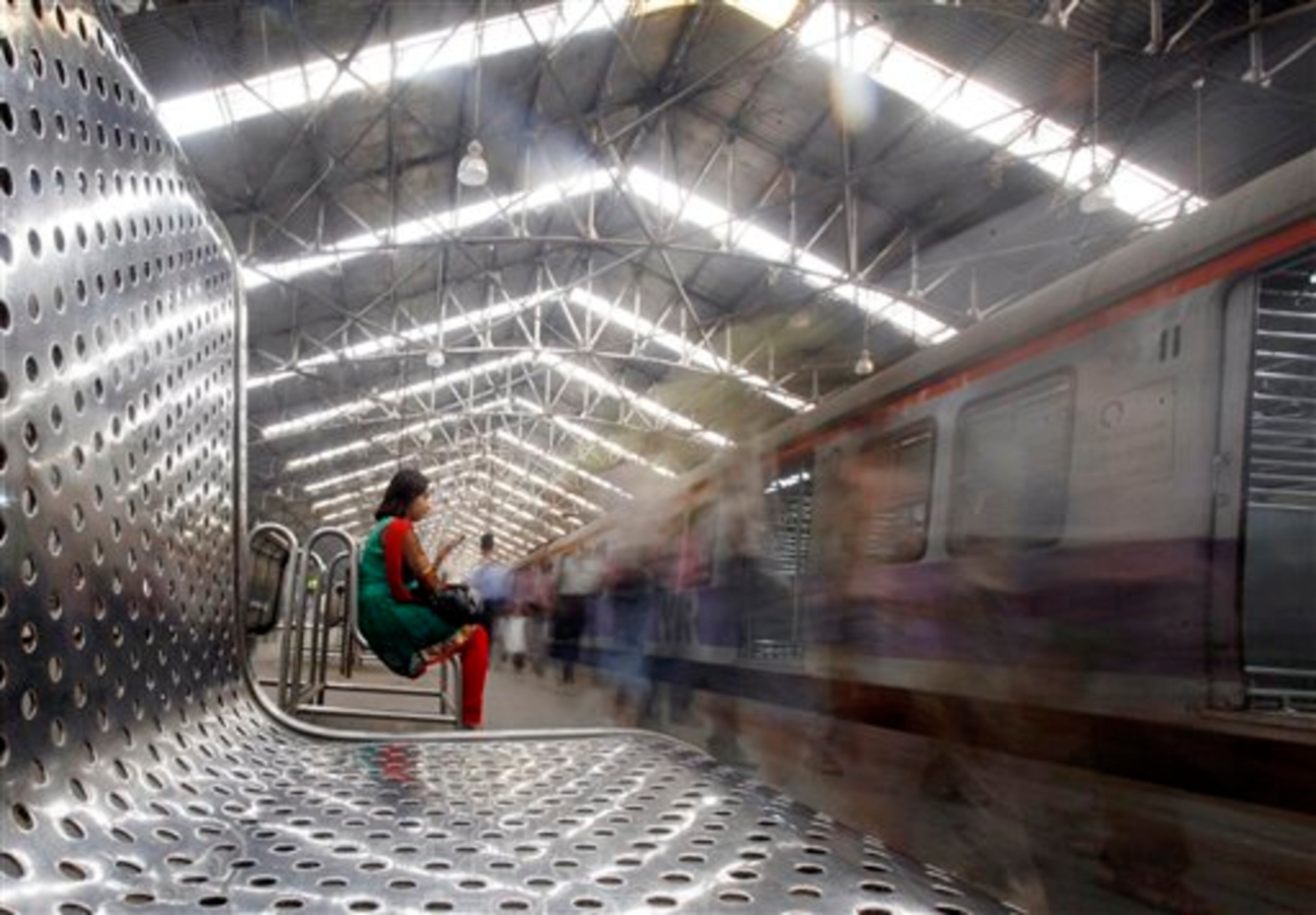 In this Feb. 11, 2013 photo taken at a slow shutter speed, a woman checks her mobile phone at a train station in Mumbai, India. Indian Railway Minister Pawan Kumar Bansal will present the country's rail budget for next fiscal year in the parliament Tuesday, Feb. 26, 2013. Indian railway network is one of the world's largest, with some 14 million passengers daily and some 40,000 miles (64,000 kilometers) of railway track cut through some of the most densely populated cities. (AP Photo/Rajanish Kakade)