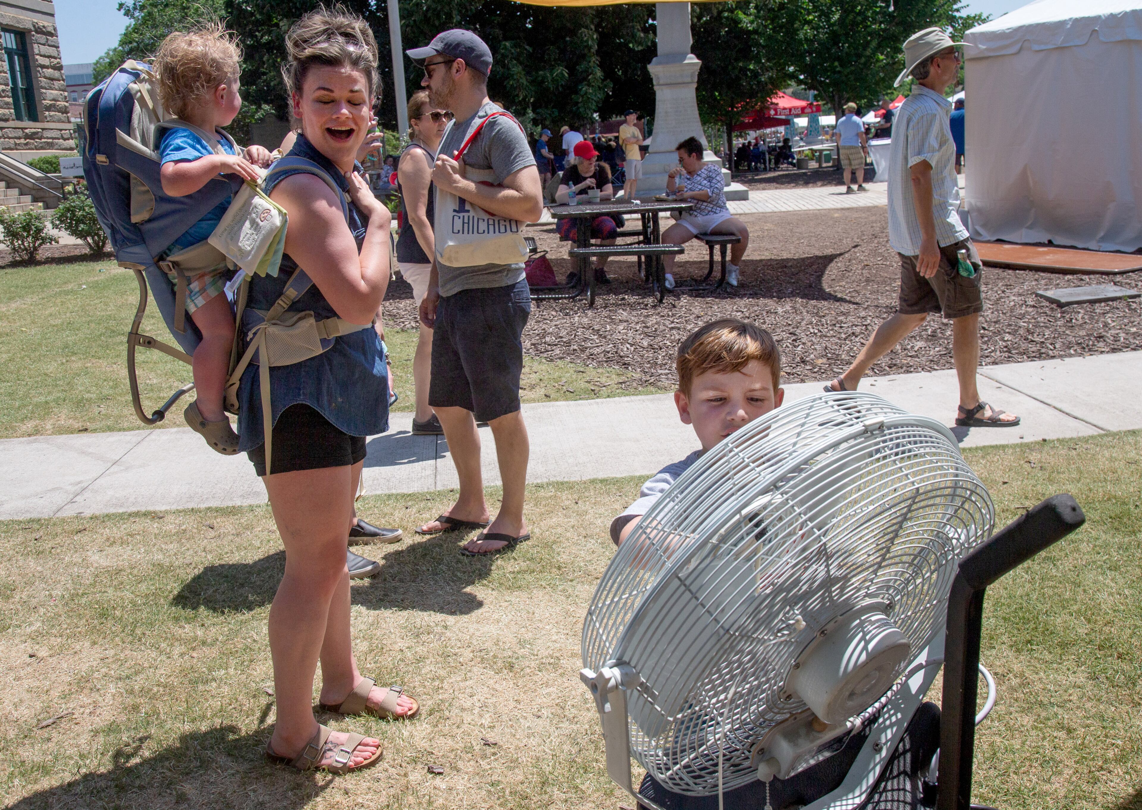 Adeline Adams and her son Jackson stand in the cool air from one of the cooling fans during the annual Decatur Arts Festival on Sunday, May 26, 2019.STEVE SCHAEFER / SPECIAL TO THE AJC