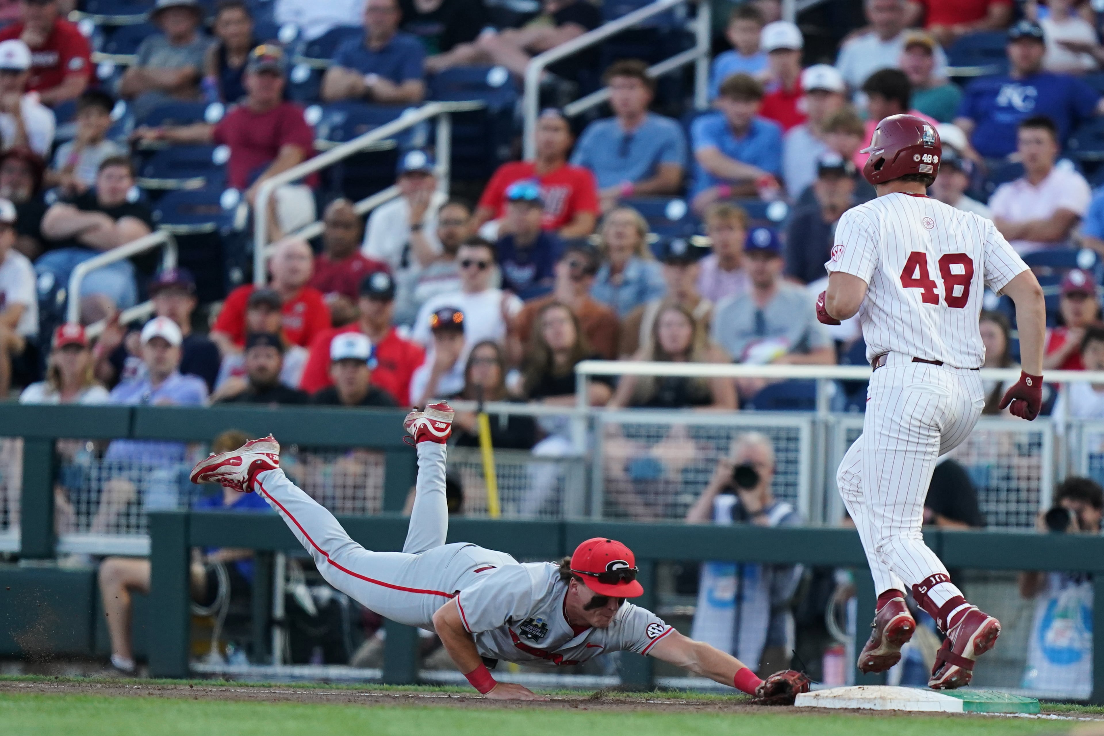 Georgia catcher Brennan Hudson (left) makes a diving play but just misses getting Oklahoma catcher Deiten Lachance out at first during their College World Series game on Monday, June 15, 2026, in Omaha, Neb. (Vera Nieuwenhuis/AP)
