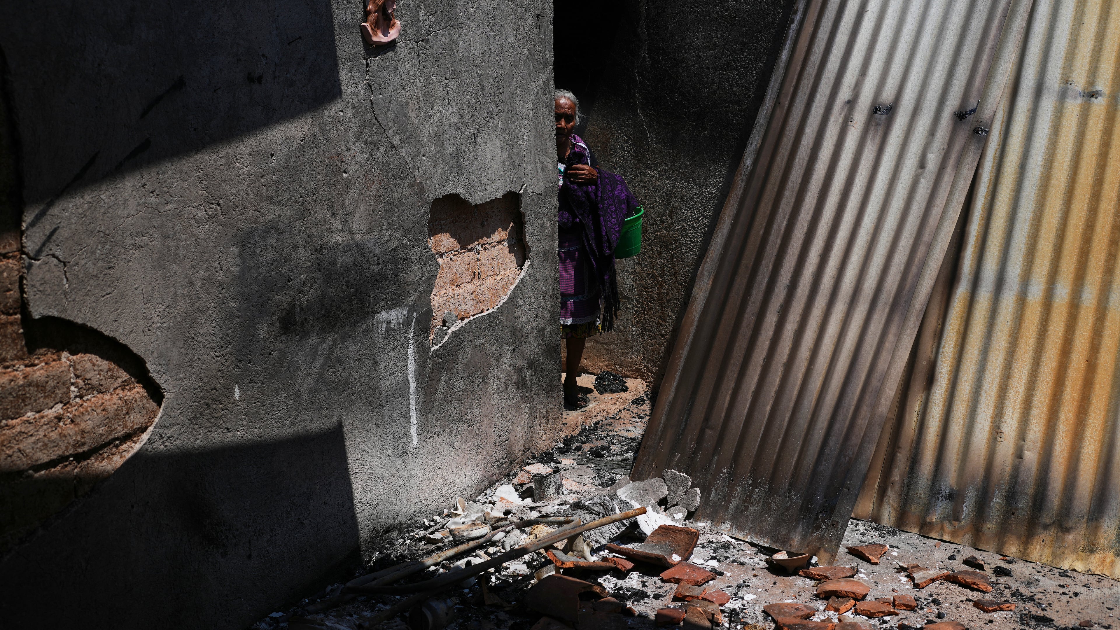 Anastasia Cabrera walks through the ruins of her home after armed attacks by local criminal groups forced dozens of residents to flee, in Tula, Mexico, Friday, May 15, 2026. (AP Photo/Marco Ugarte)