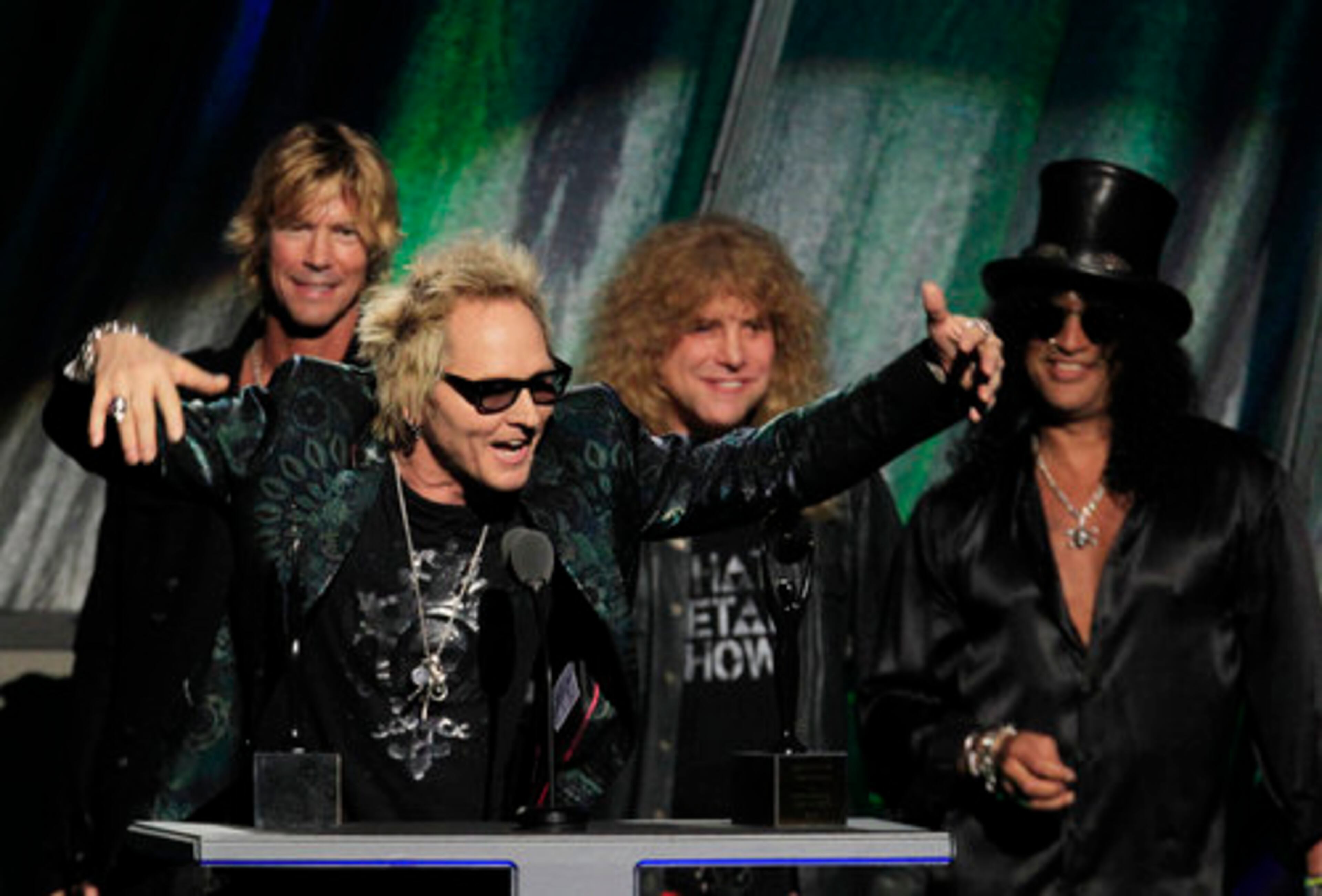 Matt Sorum gestures as Duff McKagan, back left, Steven Adler and Slash, back right, watch, after Guns N' Roses was inducted into the Rock and Roll Hall of Fame.