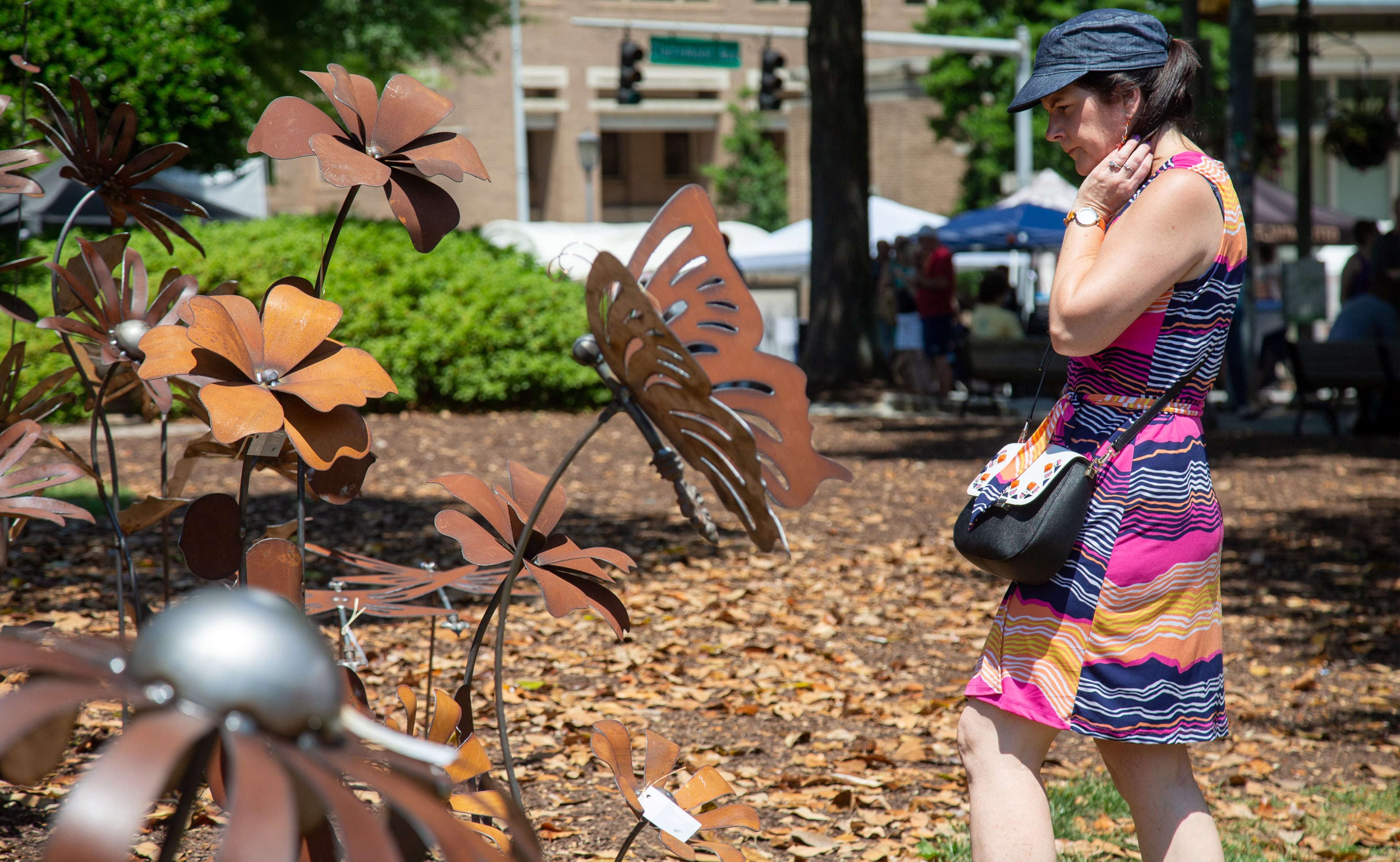 Cindy Smallwood looks over artist William Staubach's garden art sculptures during the annual Decatur Arts Festival on Sunday, May 26, 2019. STEVE SCHAEFER / SPECIAL TO THE AJC