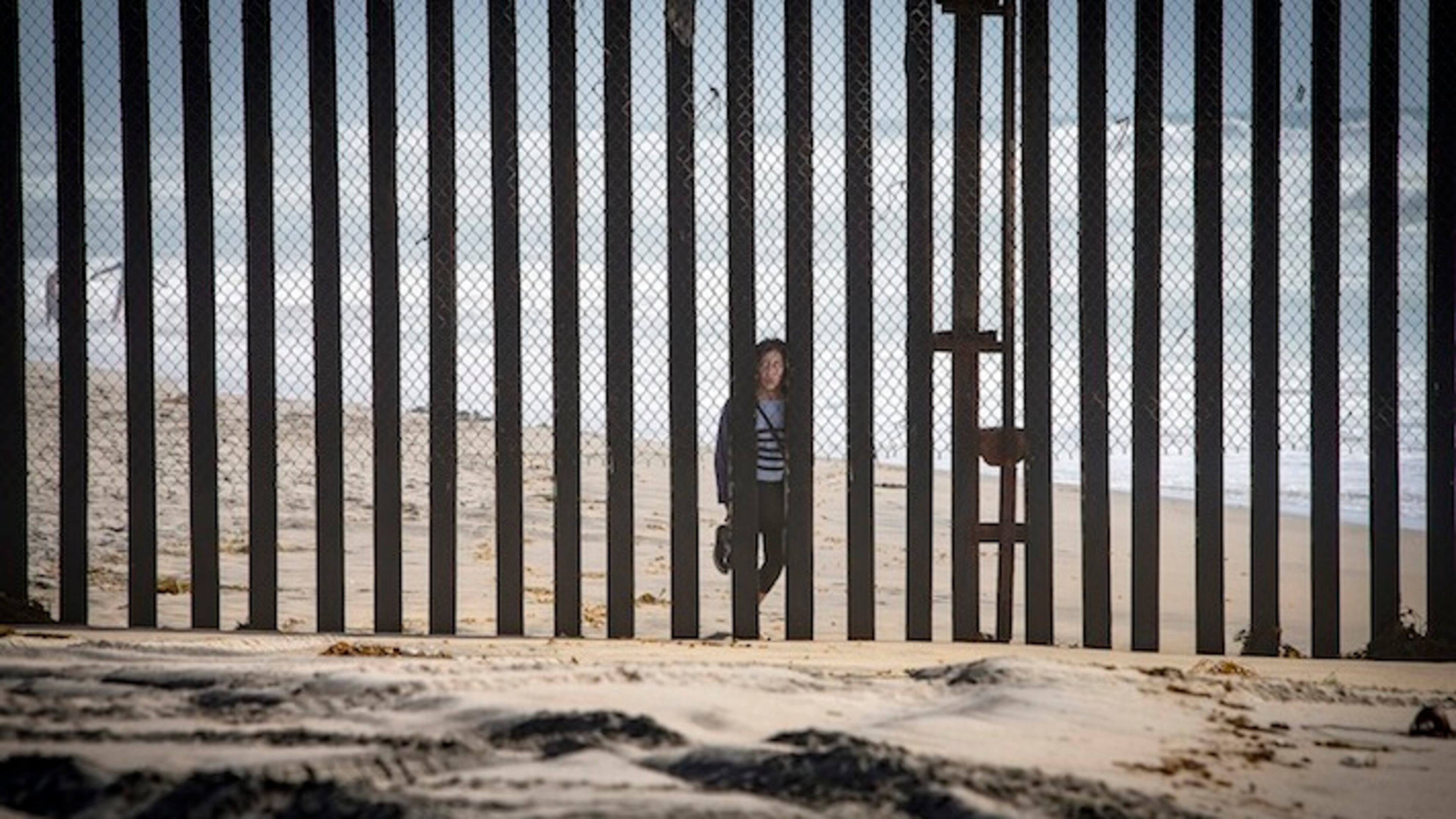 A person from Tijuana in Mexico peers through the border fence at the Border Field State Park on April 14, 2016 in Imperial Beach, Calif. (LiPo Ching/Bay Area News Group/TNS)