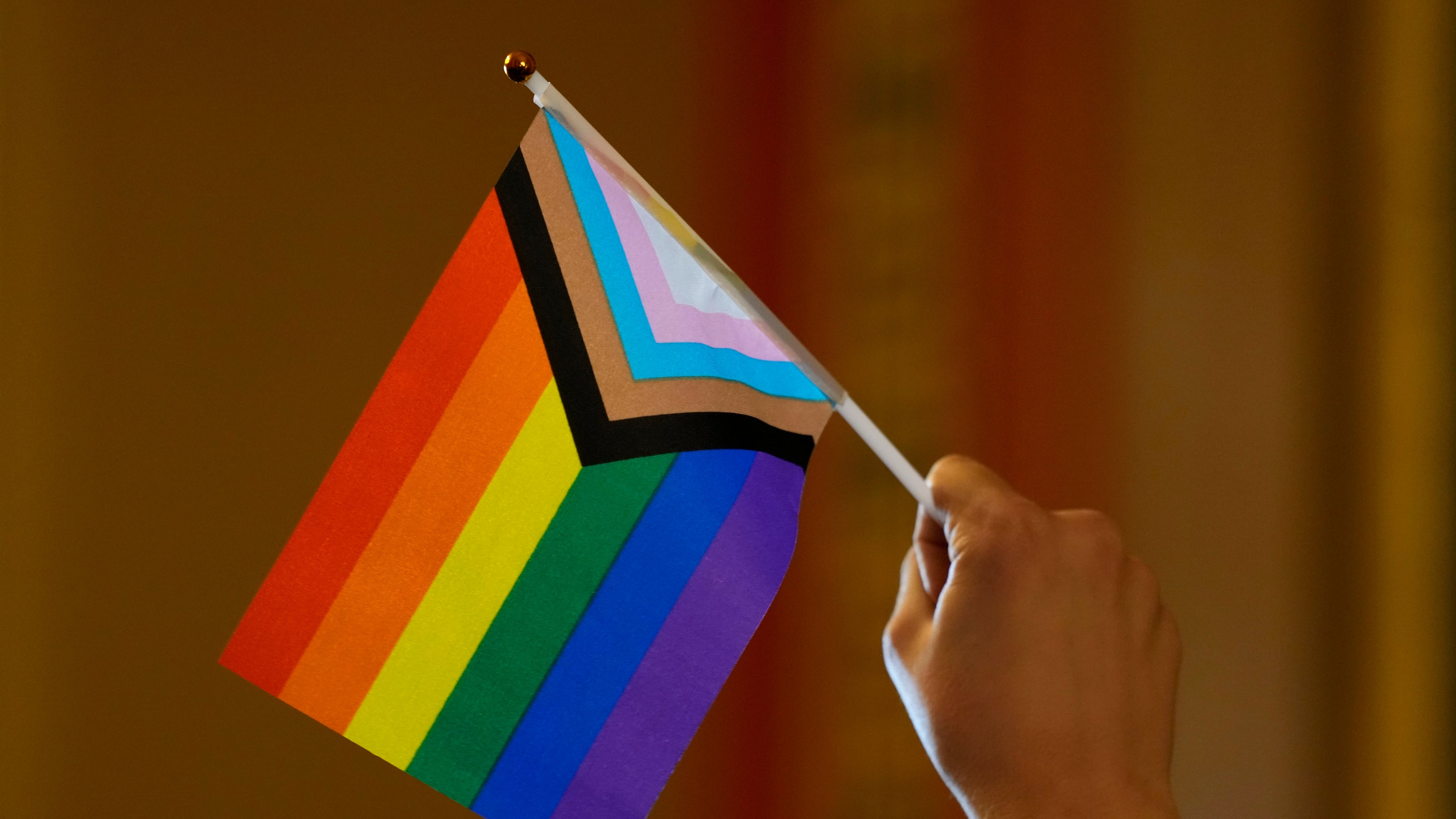 FILE - An LGBTQ+ rights supporter holds a flag in the hallway outside an Iowa House Judiciary subcommittee hearing, Jan. 31, 2024, at the Statehouse, in Des Moines, Iowa. (AP Photo/Charlie Neibergall, File)