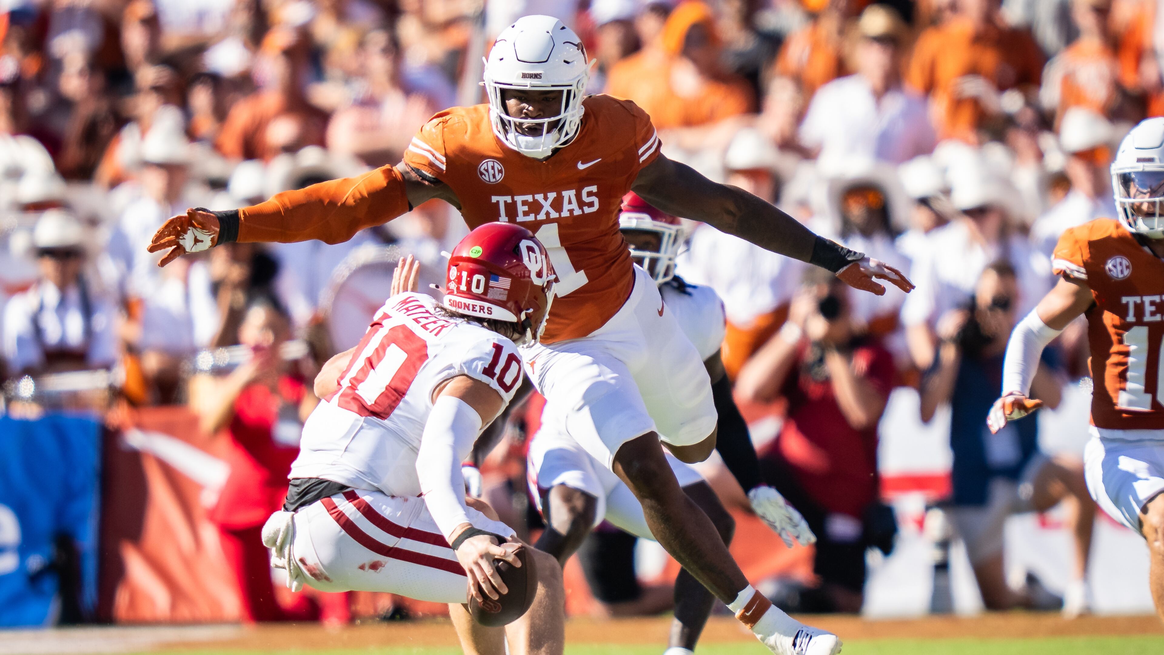 FILE - Texas linebacker Colin Simmons (1) goes to tackle Oklahoma Sooners quarterback John Mateer (10) during the second quarter of an NCAA college football game at the Cotton Bowl in Dallas, Oct. 11, 2025. (Sara Diggins/Austin American-Statesman via AP, File)