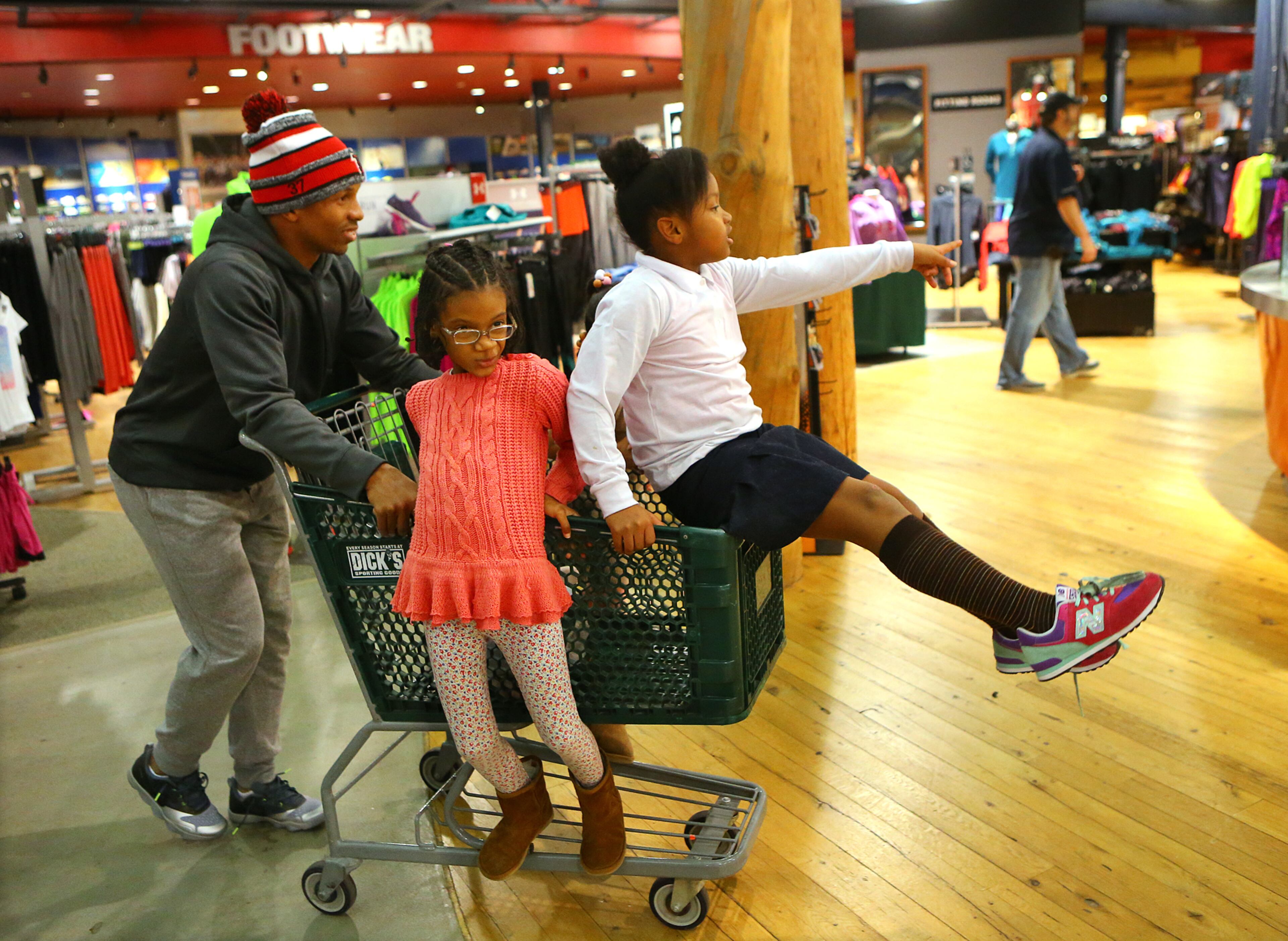 Kimora Stover, 7, points the way and Jada Butler, 8, holds on for the ride while Falcons rookie cornerback Ricardo Allen helps take kids from the Atlanta Action Ministries on a Christmas shopping spree at Dick's Sporting Goods on Tuesday, Dec. 16, 2014, in Duluth. CURTIS COMPTON / CCOMPTON@AJC.COM