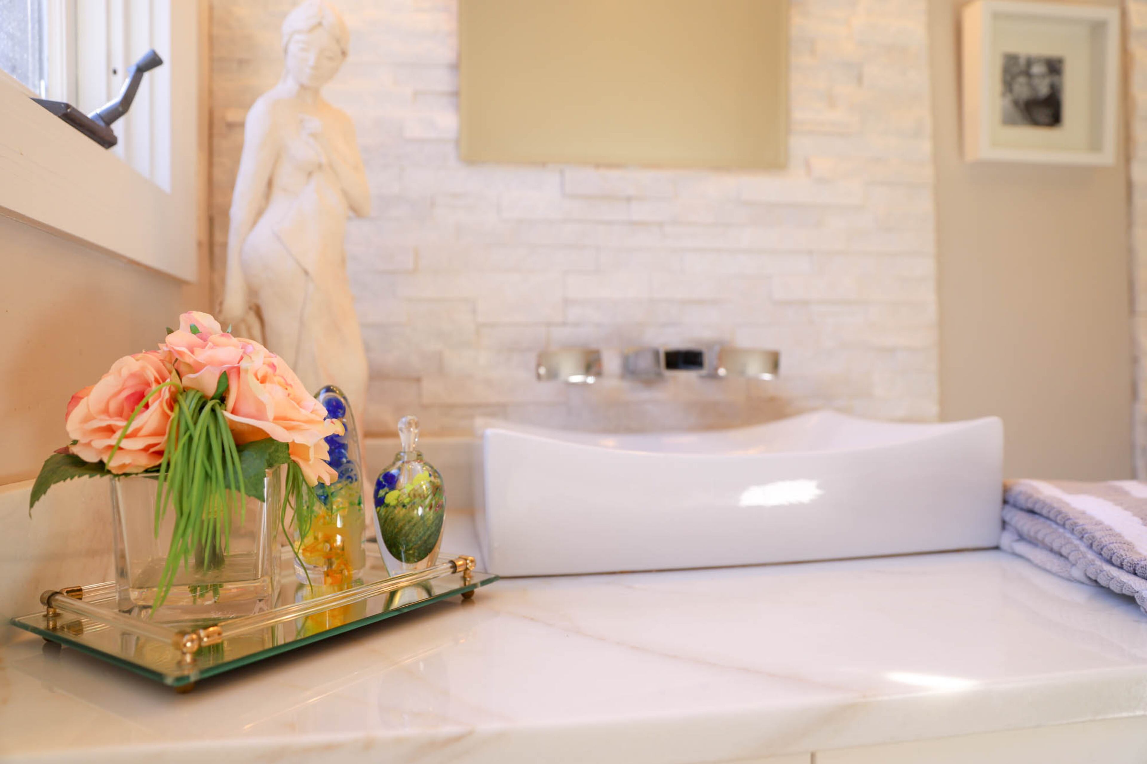 Botanical accessories add another layer of freshness to the modern makeover in the master bathroom, which also has sculpture on display.