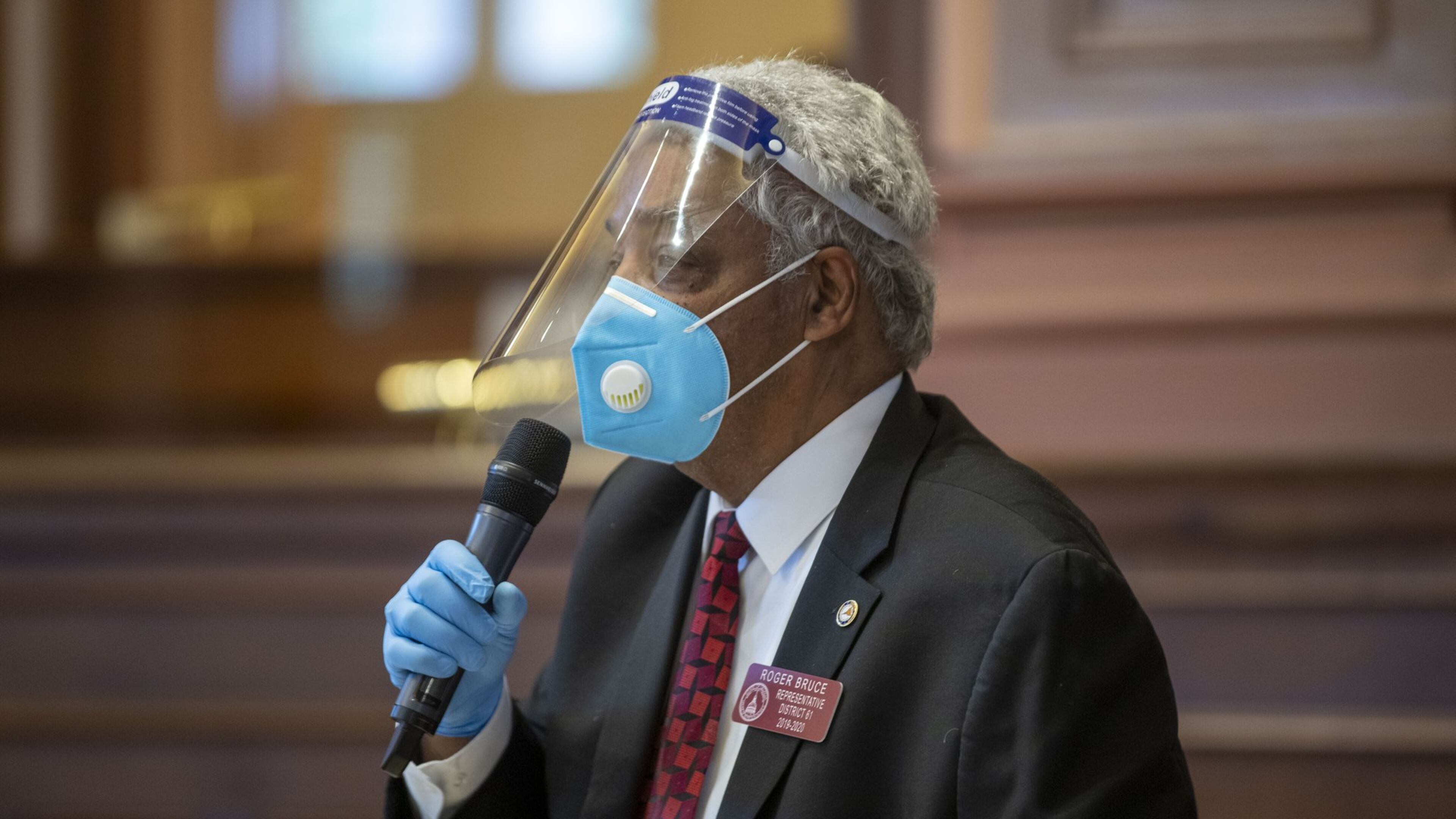 Georgia Rep. Roger Bruce, D-Atlanta, wears a face shield, gloves and mask while speaking in favor a bill after the General Assembly returned this month to complete the session it suspended in mid-March because of the coronavirus pandemic. (ALYSSA POINTER / ALYSSA.POINTER@AJC.COM)