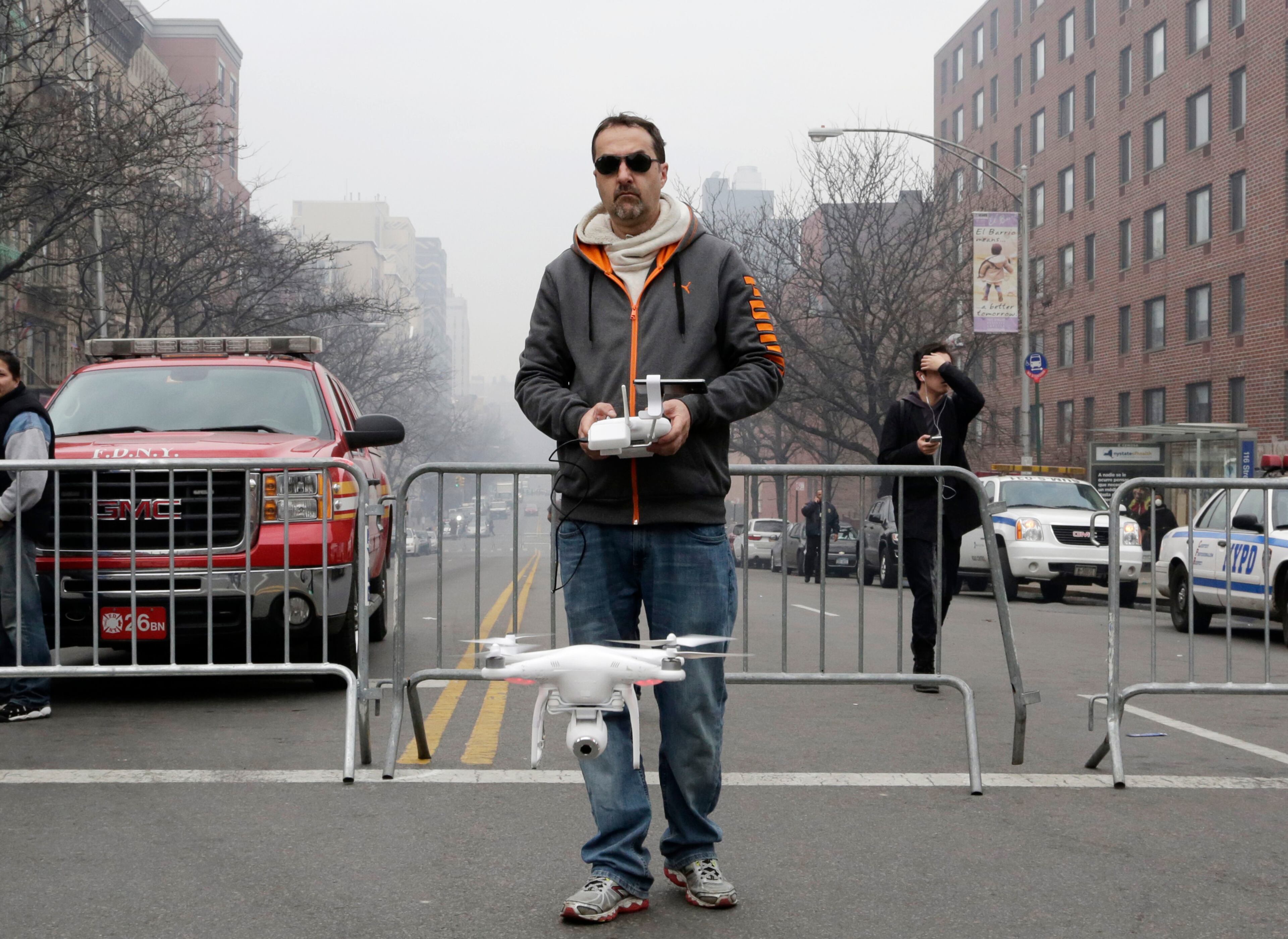 Brian Wilson launches a small drone equipped with a video camera to fly over the scene of an explosion an explosion that leveled two apartment buildings in East Harlem, Wednesday, March 12, 2014, in New York. Wilson says he uses the aerial drone to document buildings, weddings and news events. (AP Photo/Mark Lennihan)