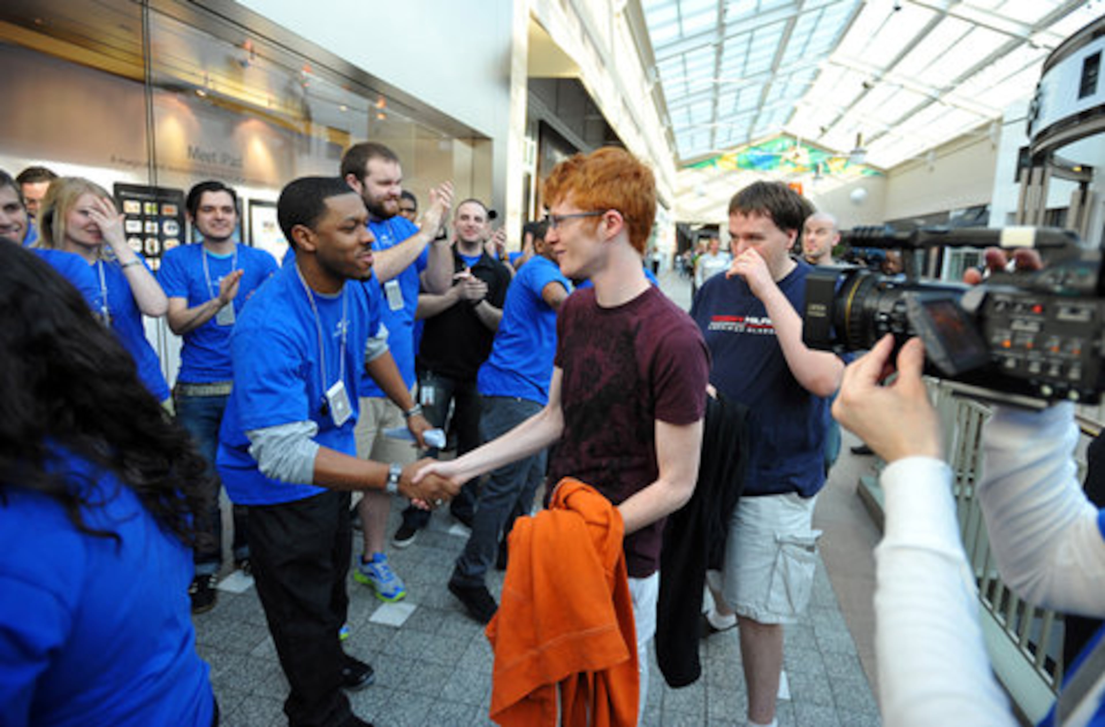 Apple Store employee Jeremy Gill greets the first customer of the day, Chris Pairan, who arrived at the mall before the 9 a.m. opening to get a spot at the front of the line.